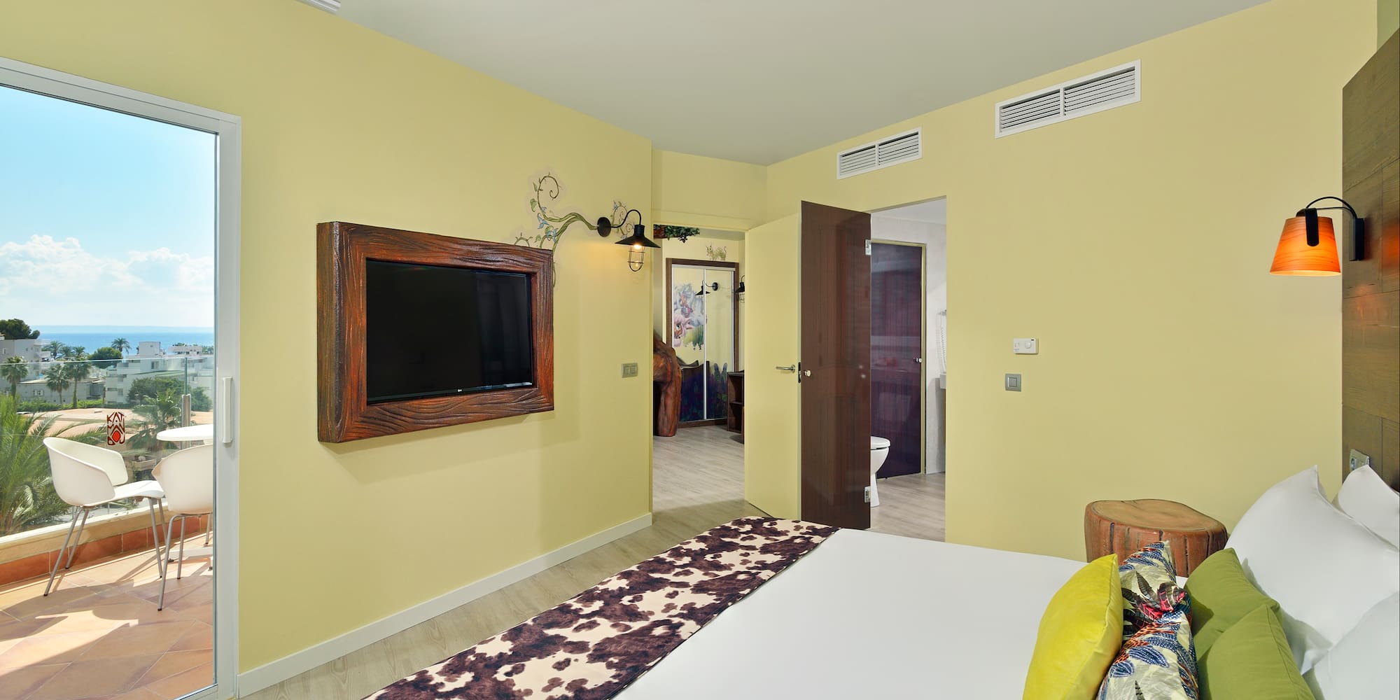 Modern hotel bedroom with ocean view balcony and cowhide bed runner.