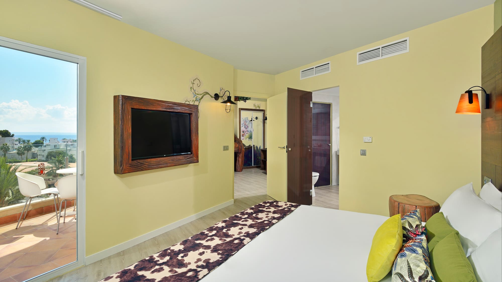 Modern hotel bedroom with ocean view balcony and cowhide bed runner.