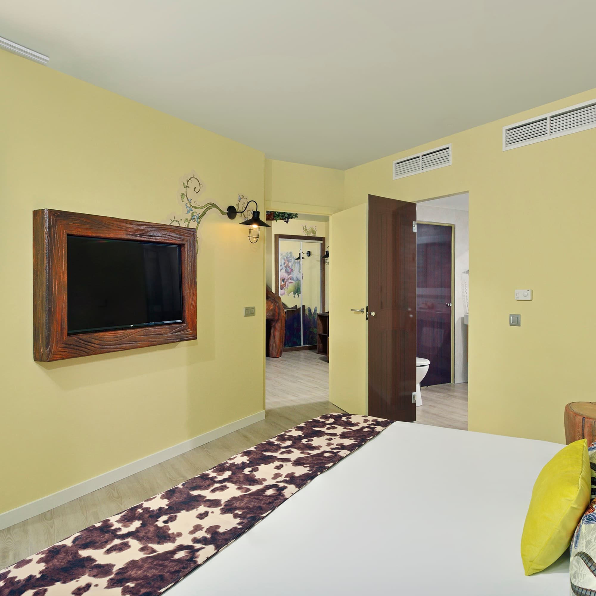 Modern hotel bedroom with ocean view balcony and cowhide bed runner.