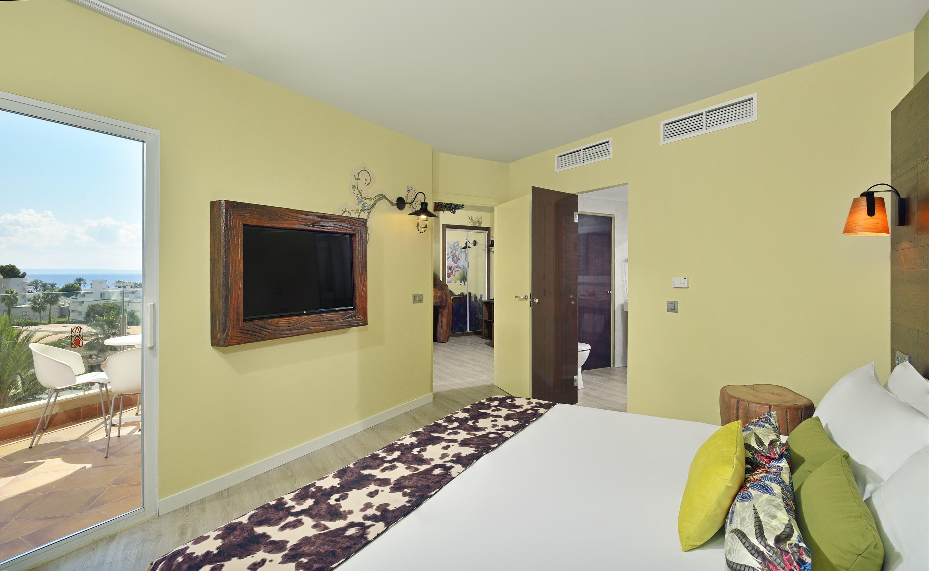 Modern hotel bedroom with ocean view balcony and cowhide bed runner.