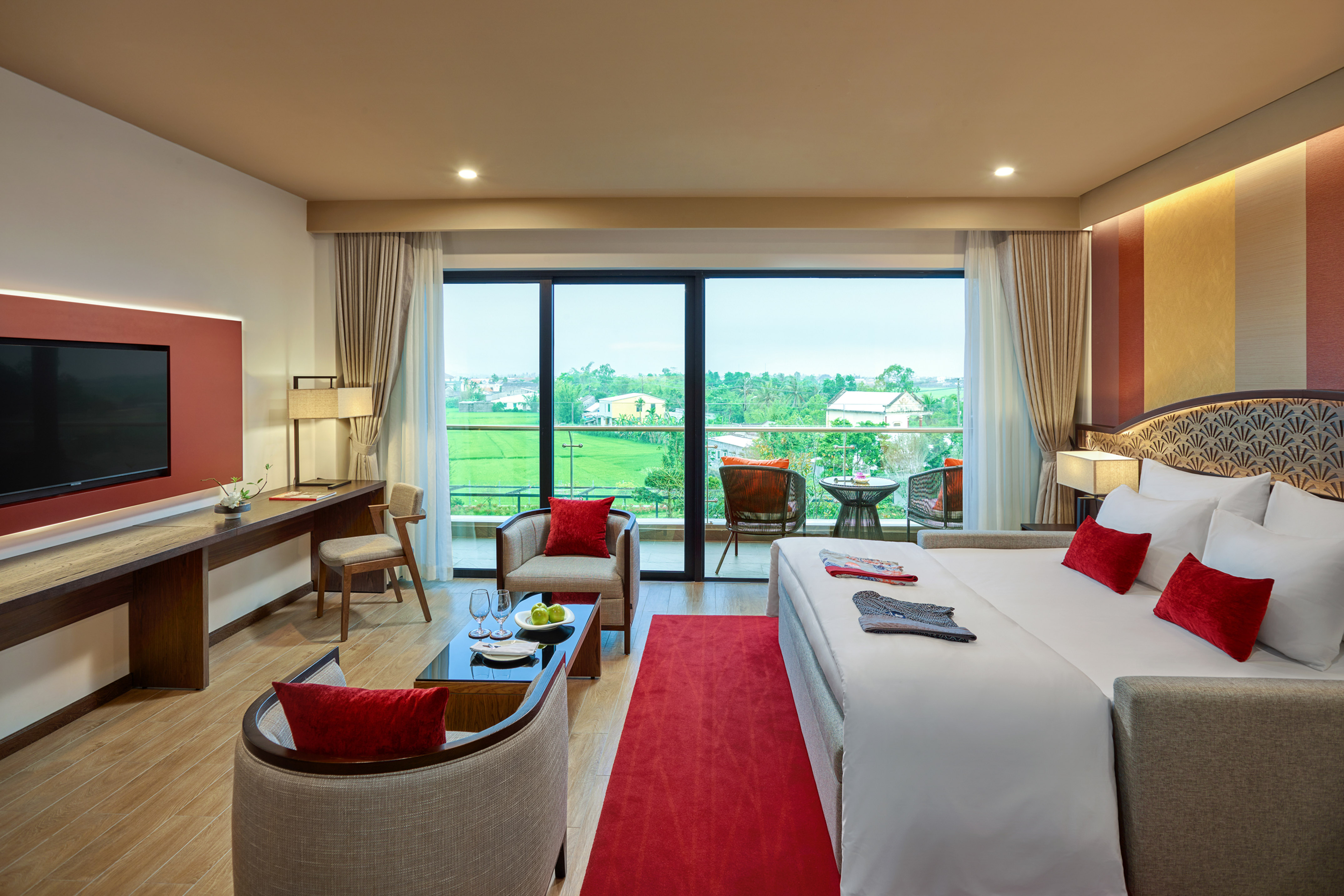 Luxury hotel room with king bed, balcony, and scenic rice field view.