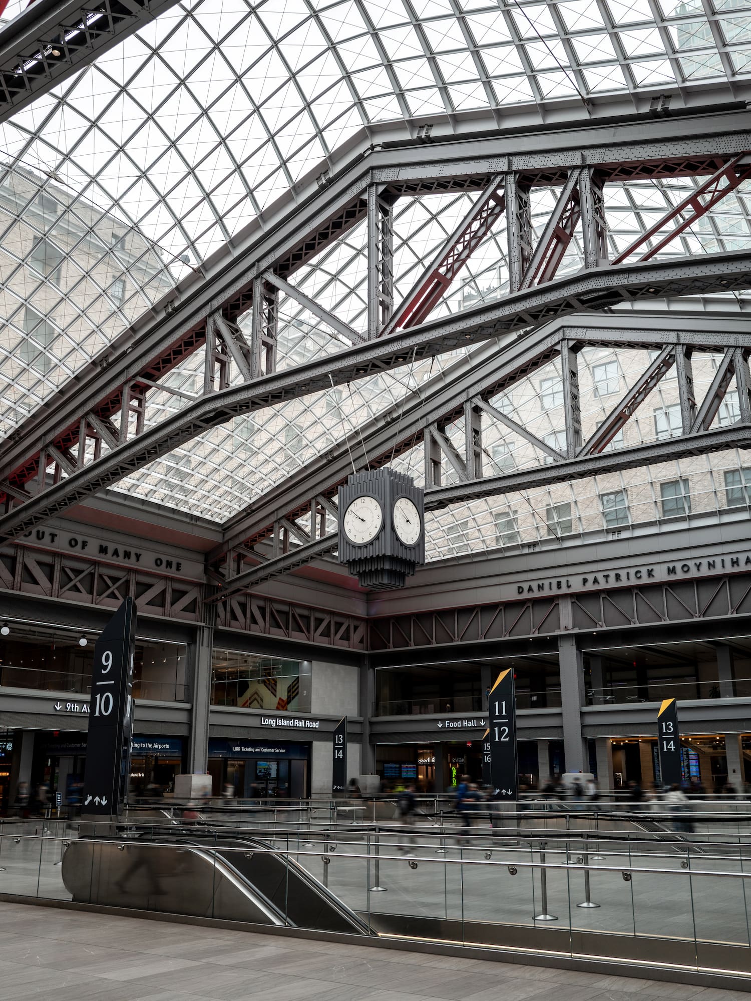 Moynihan Train Hall interior with vaulted glass ceiling, LIRR signs, and clock.