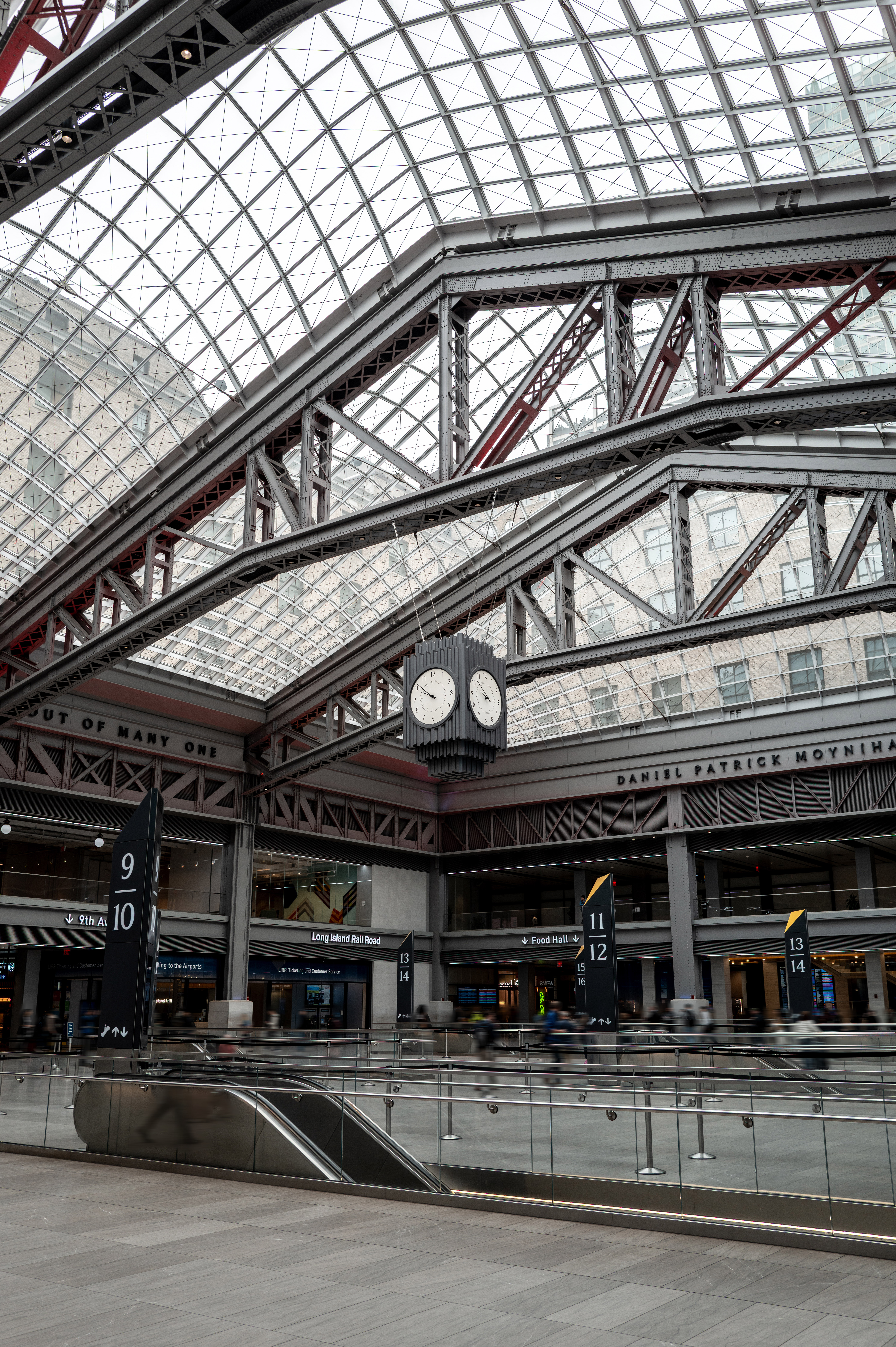 Moynihan Train Hall interior with vaulted glass ceiling, LIRR signs, and clock.