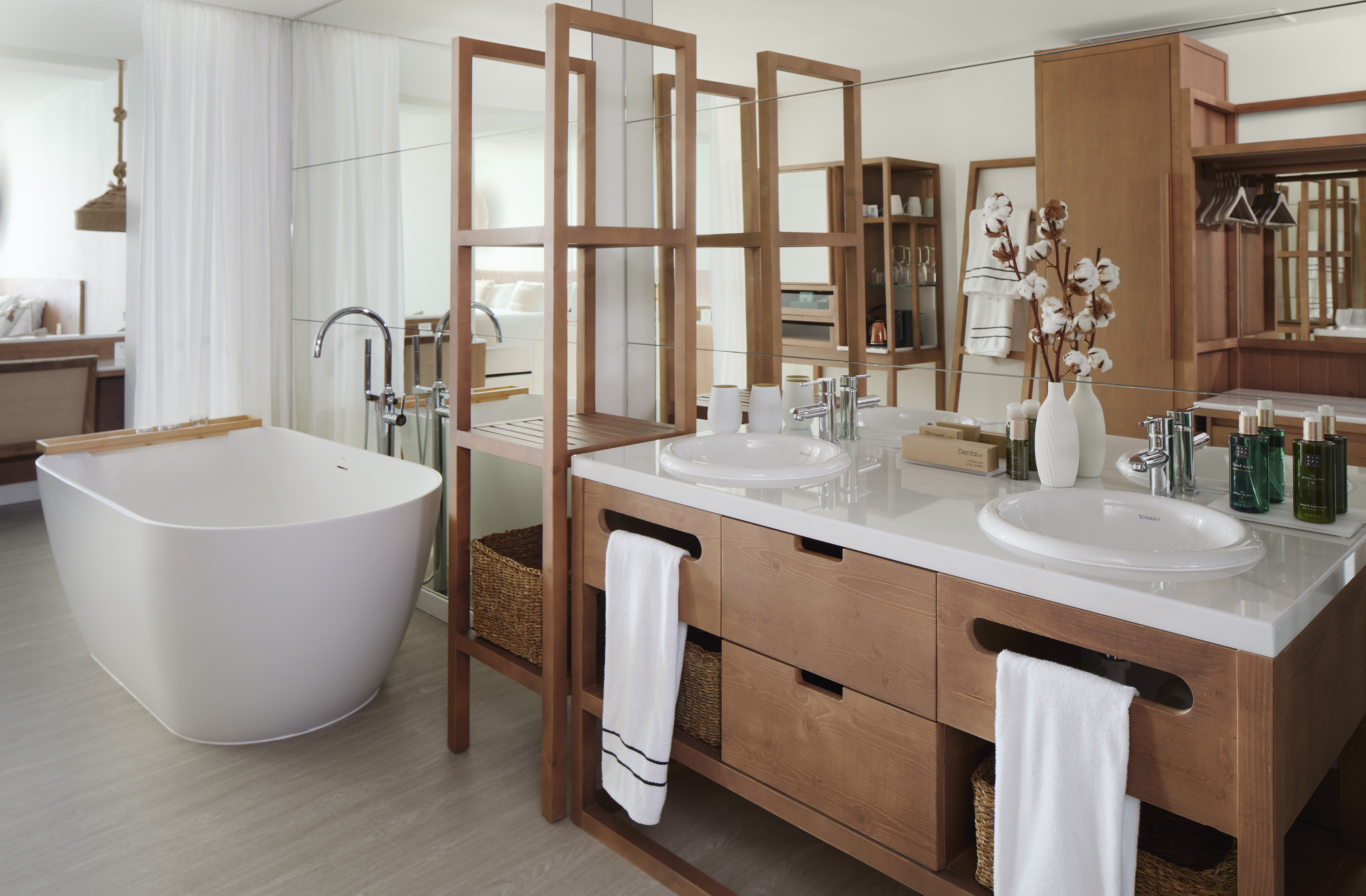 Modern luxury bathroom featuring freestanding tub, double wood vanity, and spa amenities.