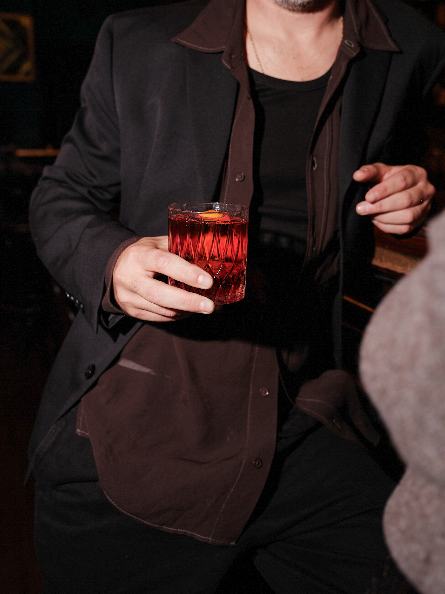 Man holding Negroni cocktail in a patterned glass at a bar.