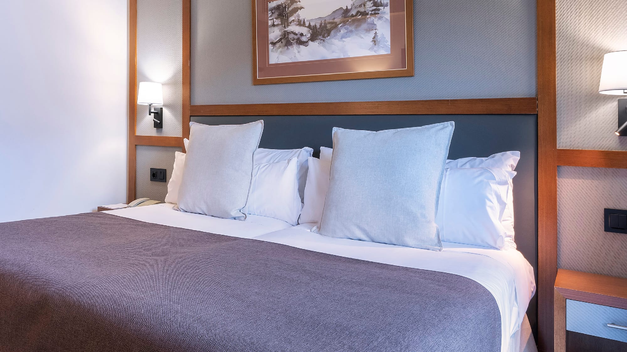 a bed with pillows and a picture on the wall