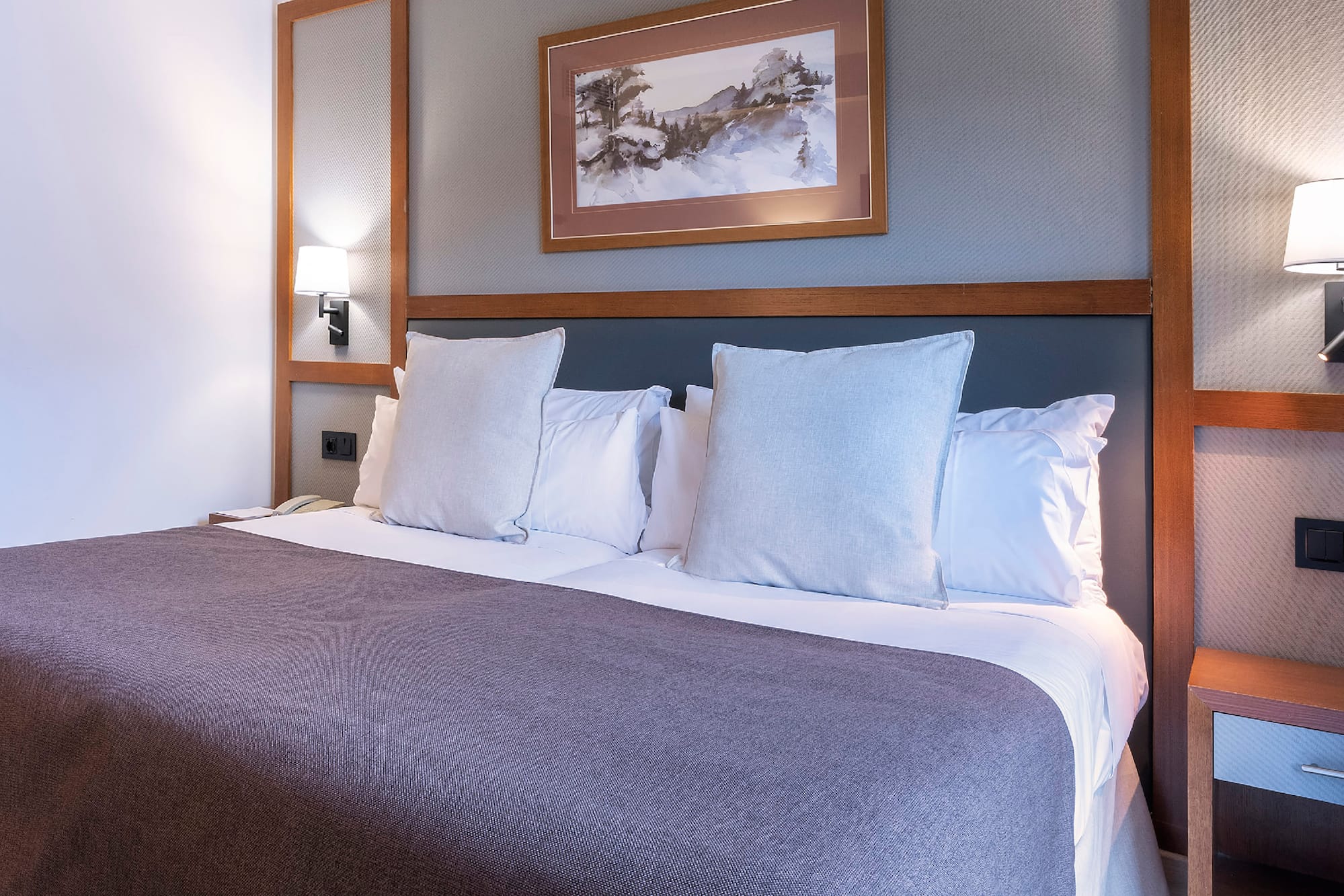 a bed with pillows and a picture on the wall