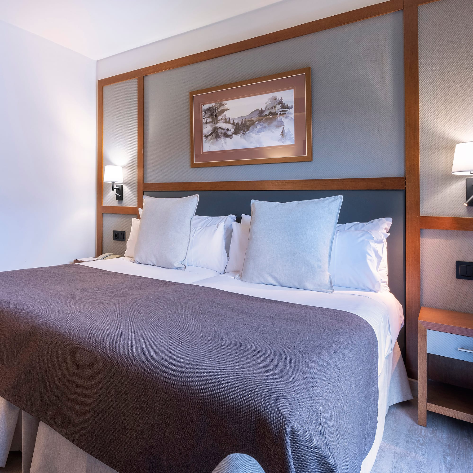 a bed with pillows and a picture on the wall