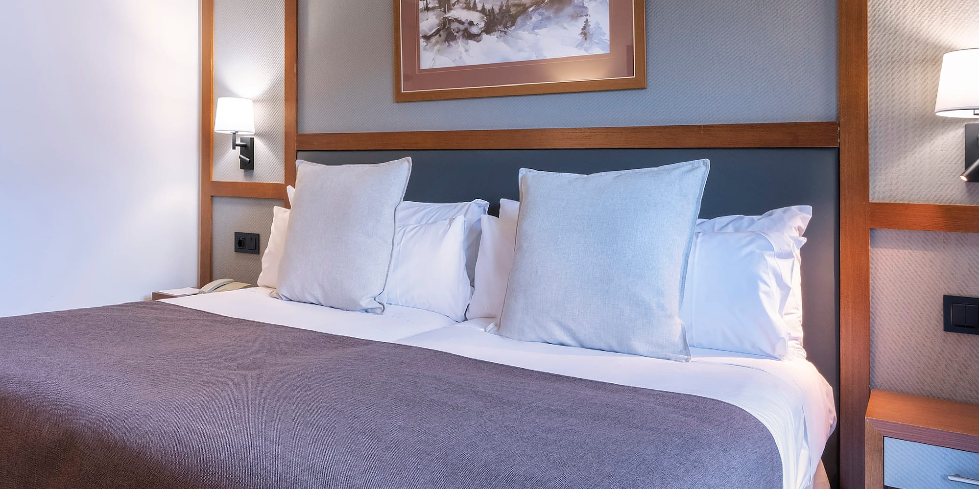 a bed with pillows and a picture on the wall