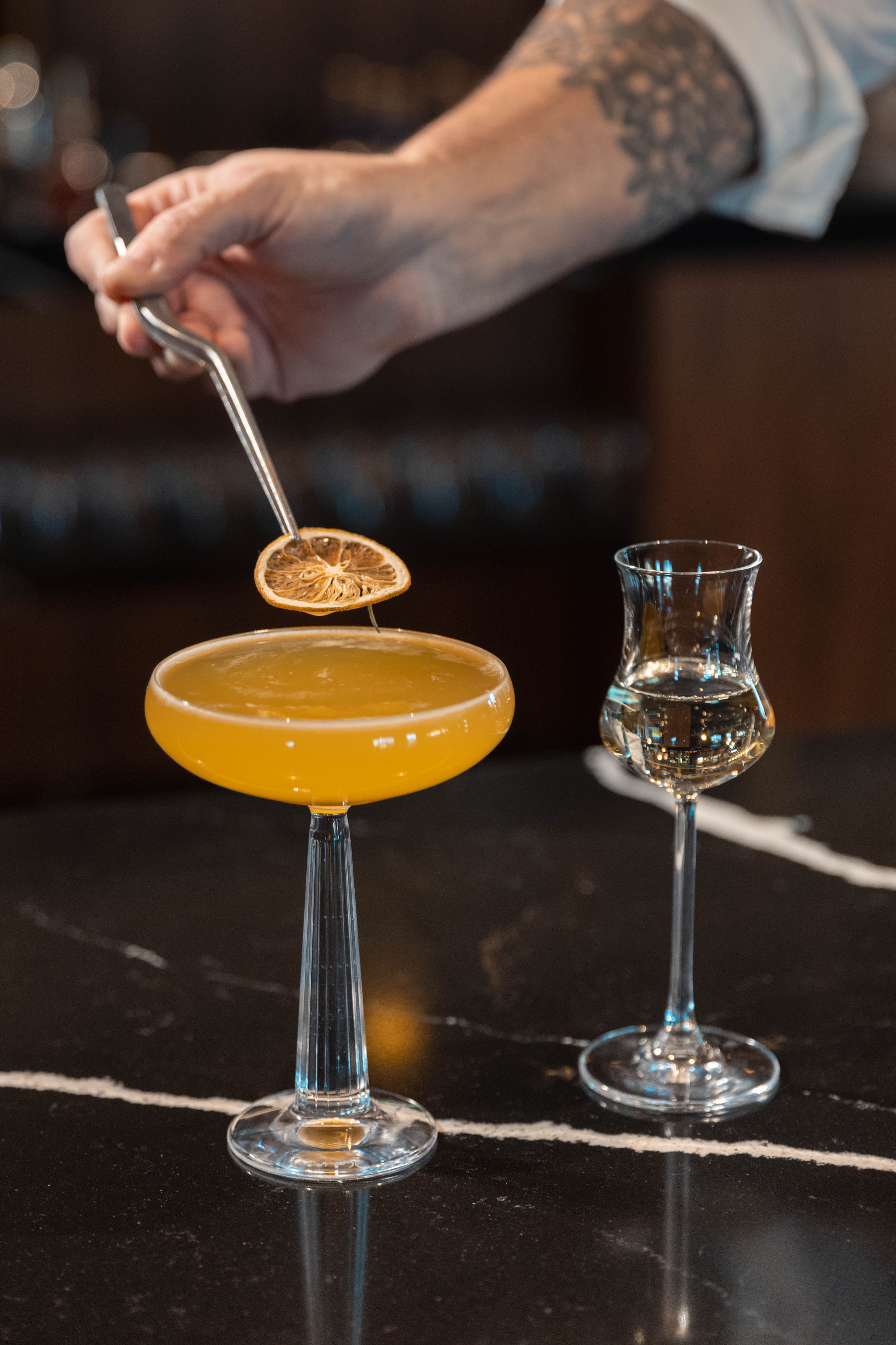 a person holding a lemon over a glass of liquid