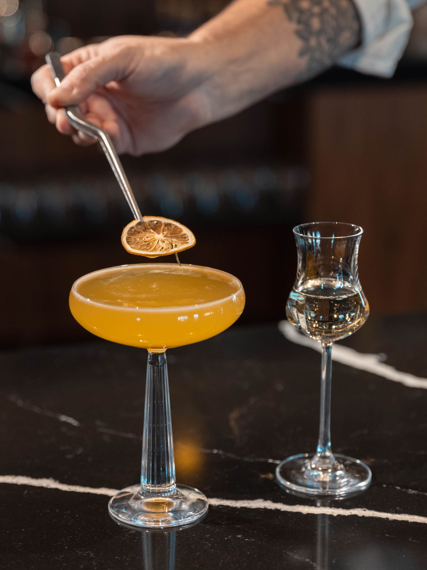 a person holding a lemon over a glass of liquid