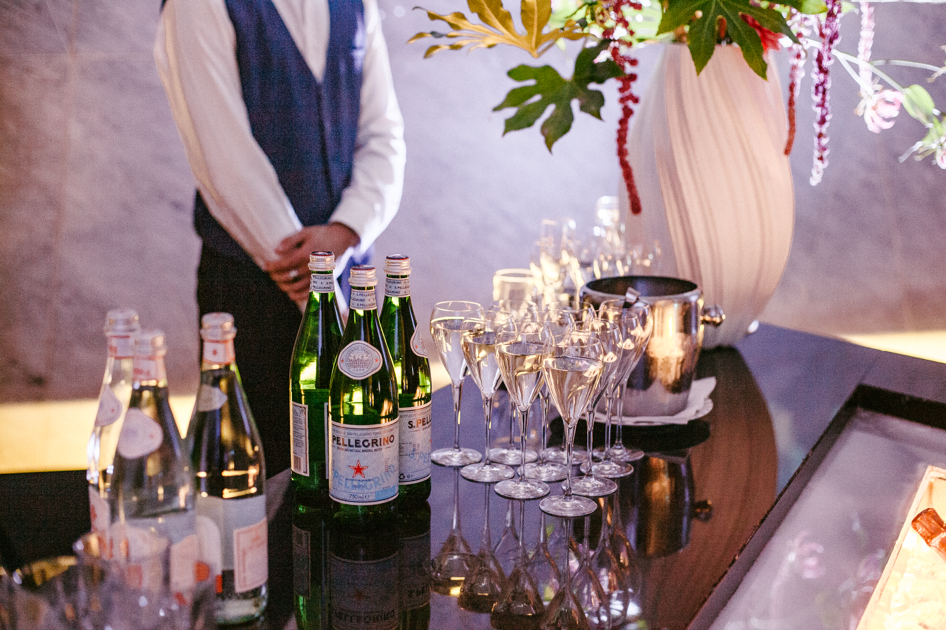 S.Pellegrino sparkling water bottles, filled glasses, and server at event bar.
