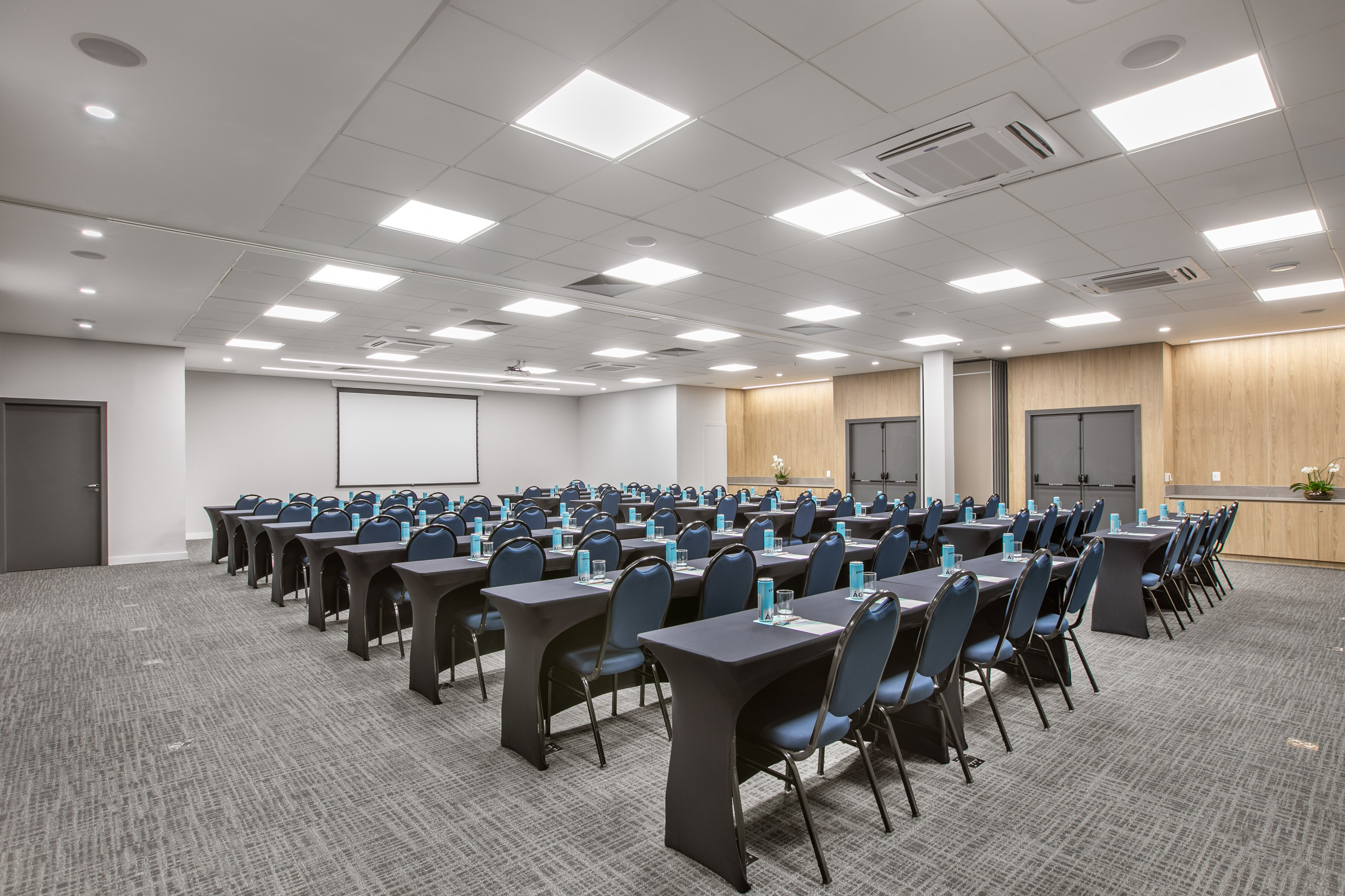 Conference room: modern setup with blue chairs, tables, and projector.