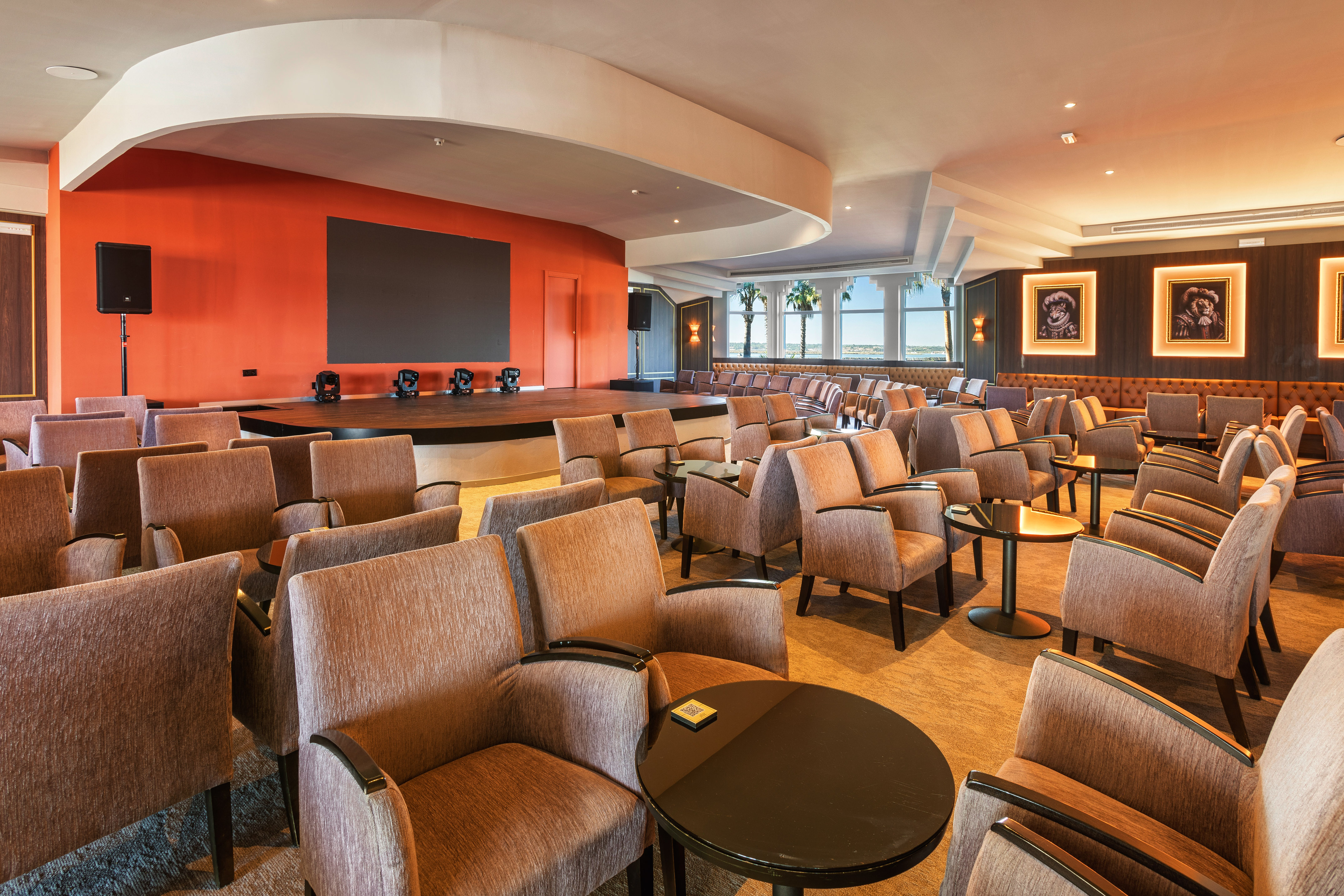 Resort conference hall with stage, large screen, and comfortable seating for events.