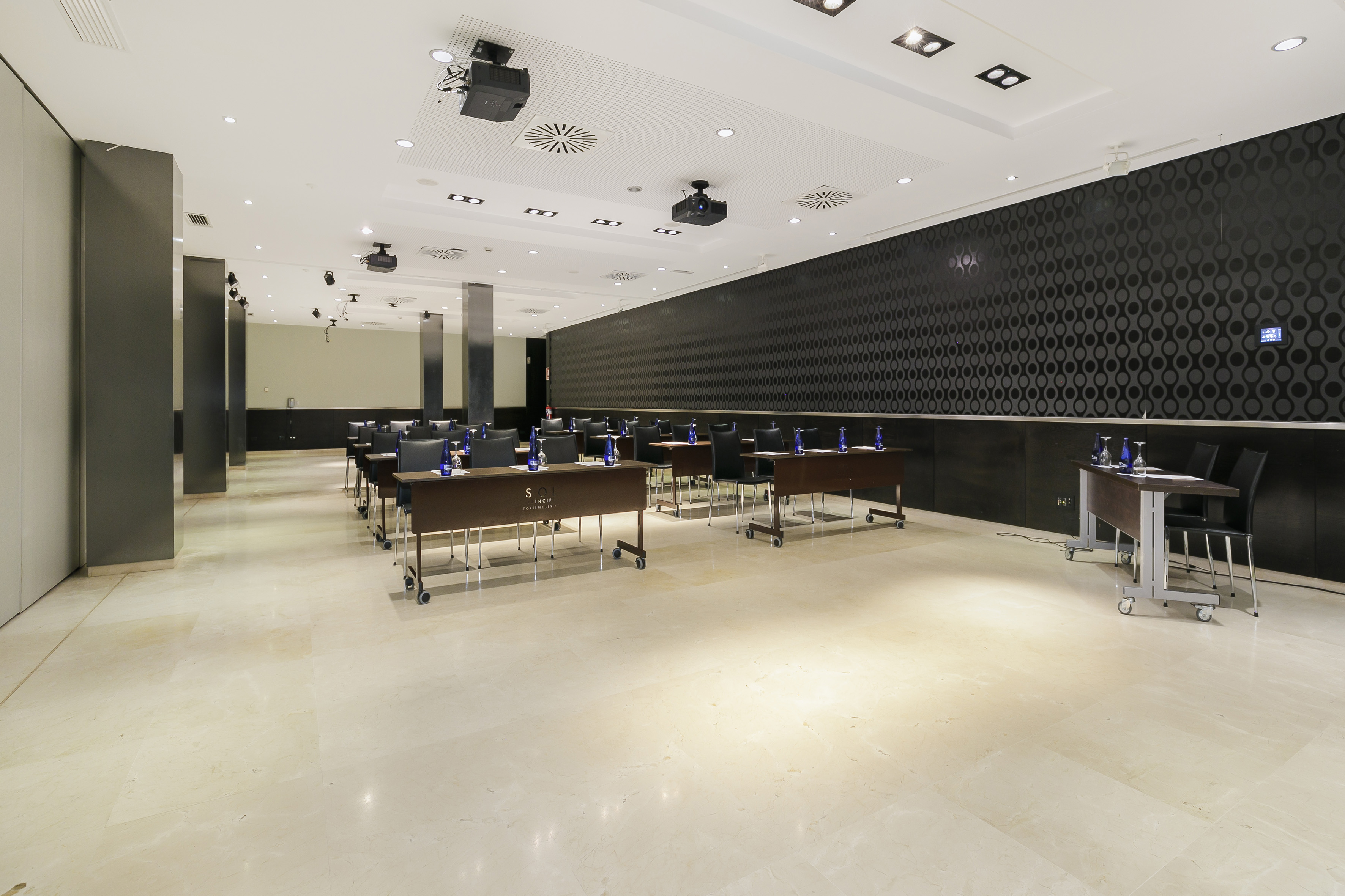 Empty modern conference room with tables, chairs, and ceiling projectors.