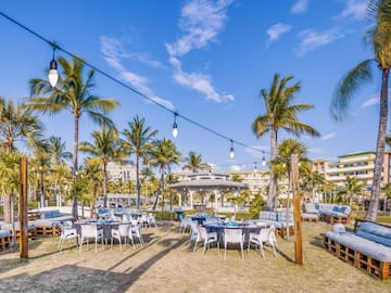 a group of tables and chairs in a yard with palm trees