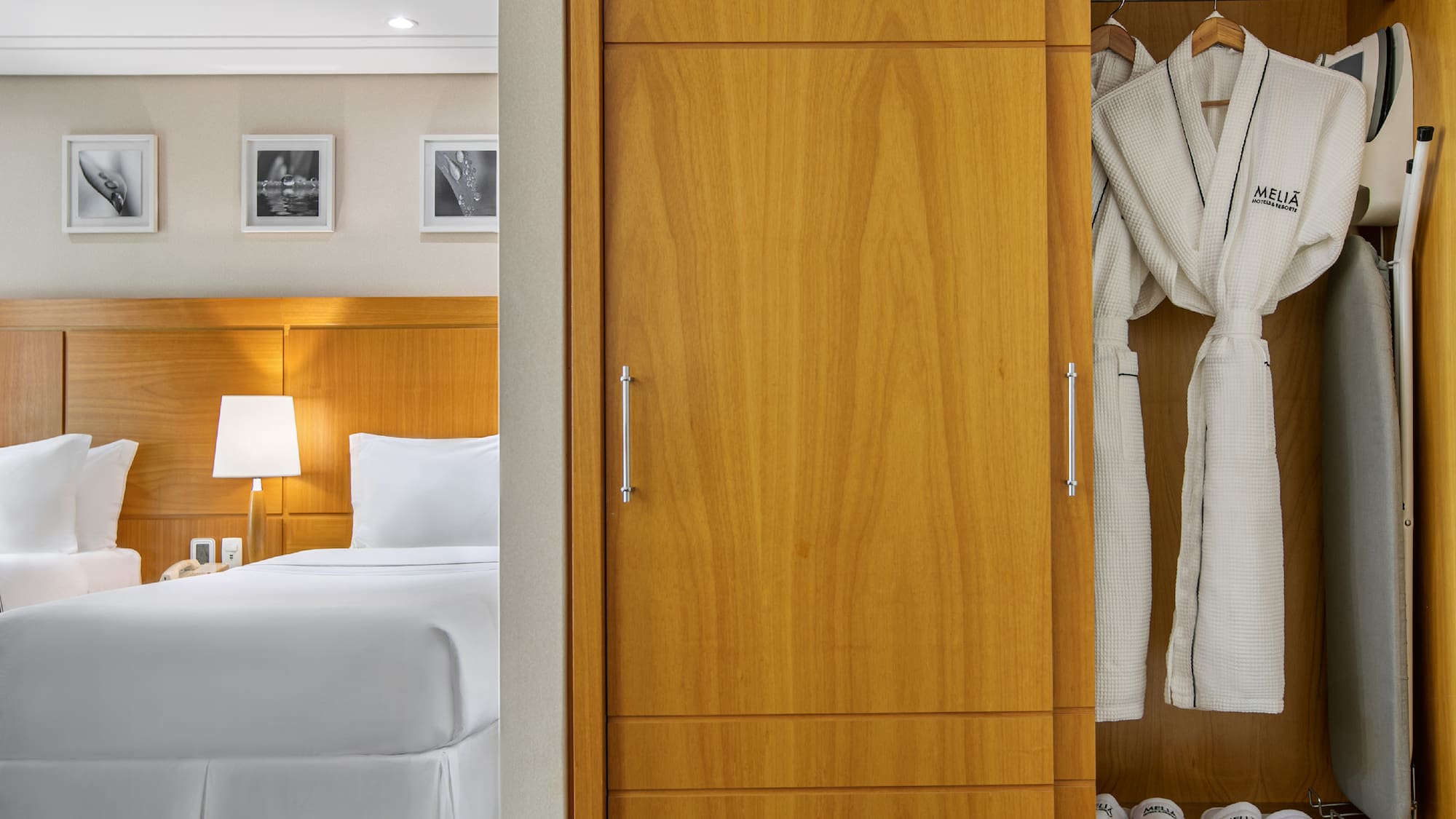 a closet with white bathrobes and a bed