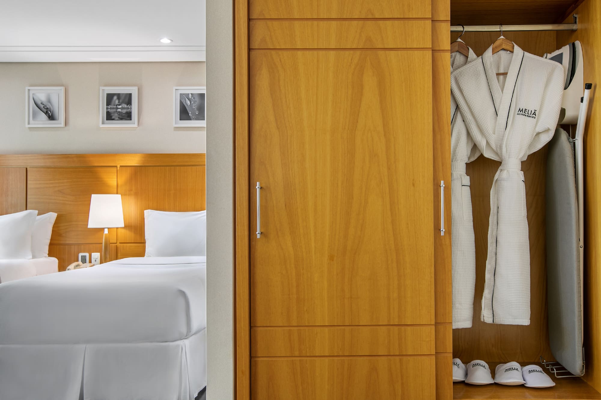 a closet with white bathrobes and a bed