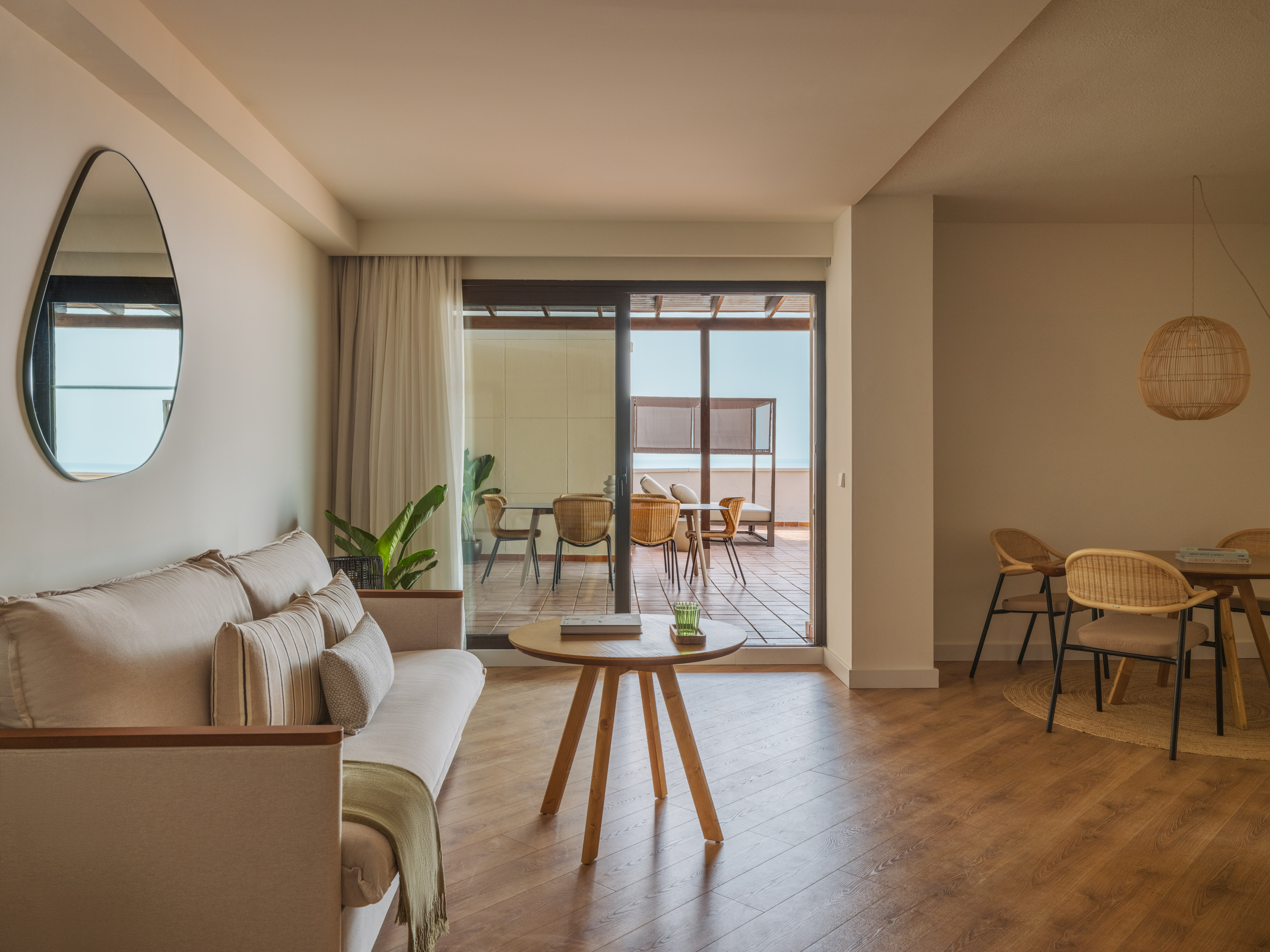 Modern living room with beige sofa, wooden table, hardwood floor, and balcony.