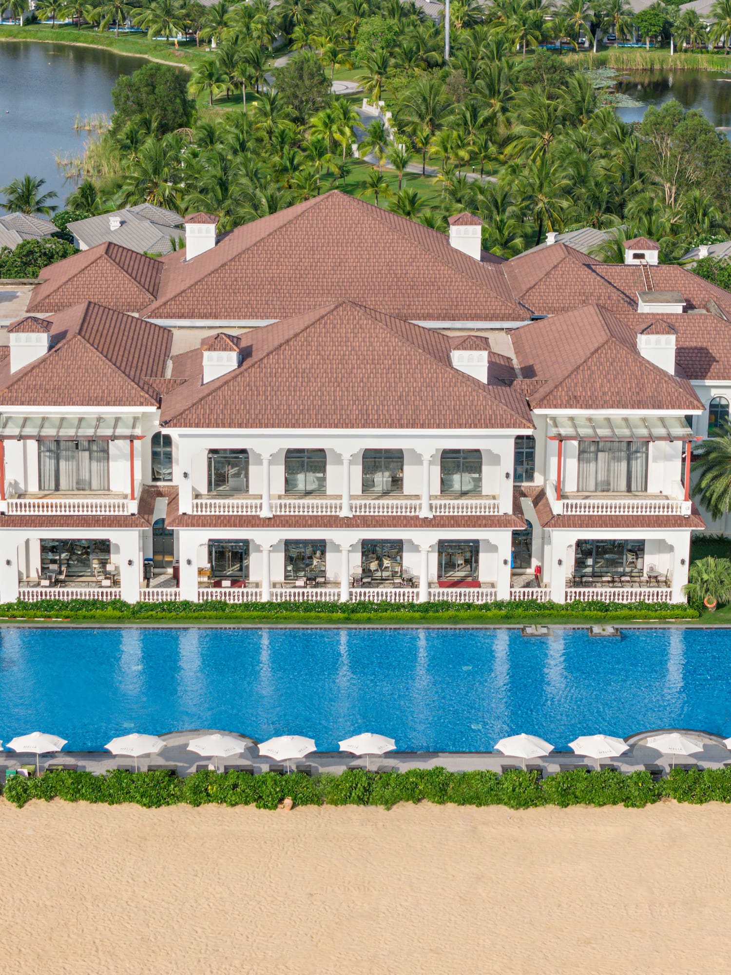 a large white building with a pool and trees