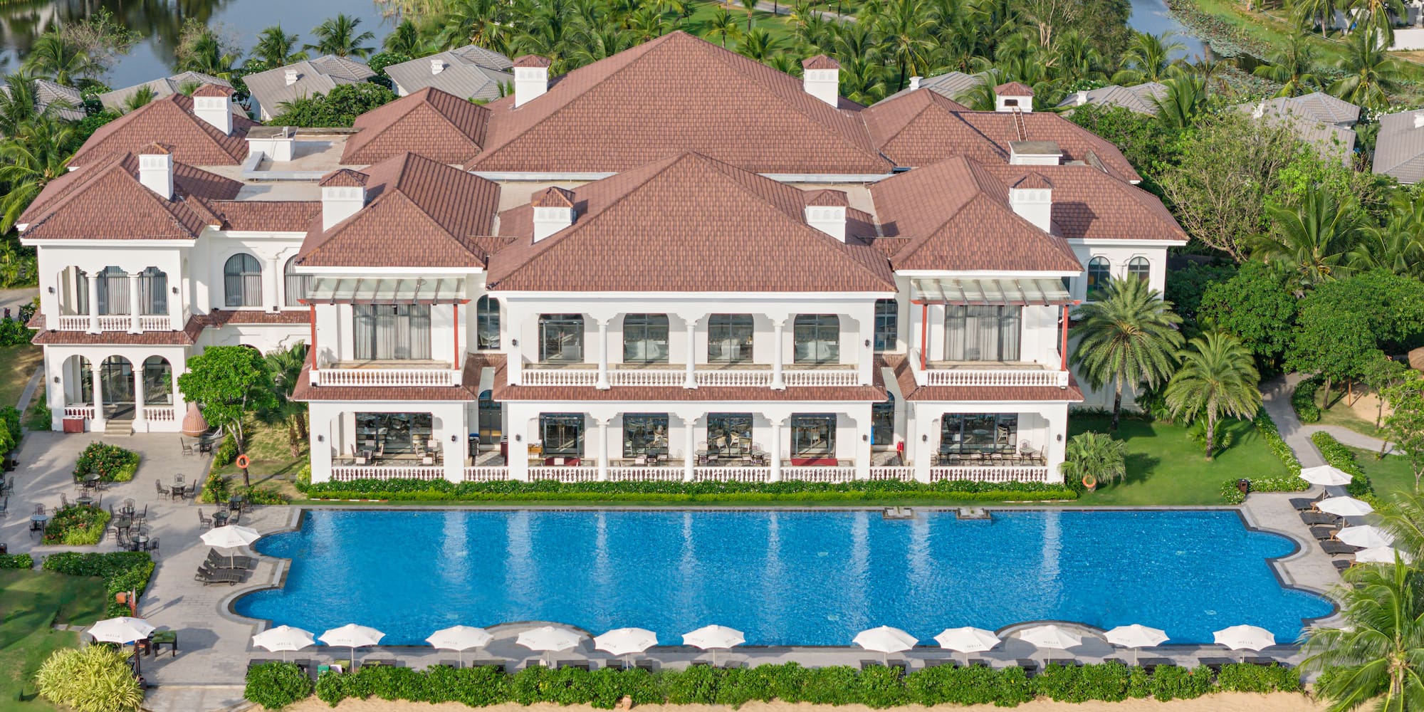 a large white building with a pool and trees