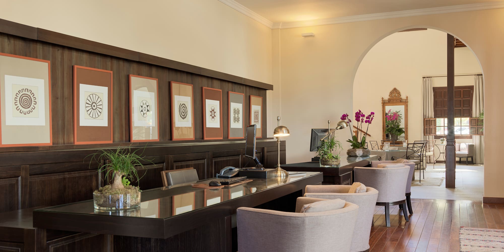 Elegant hotel reception desk with computers, framed art, and warm wood tones.