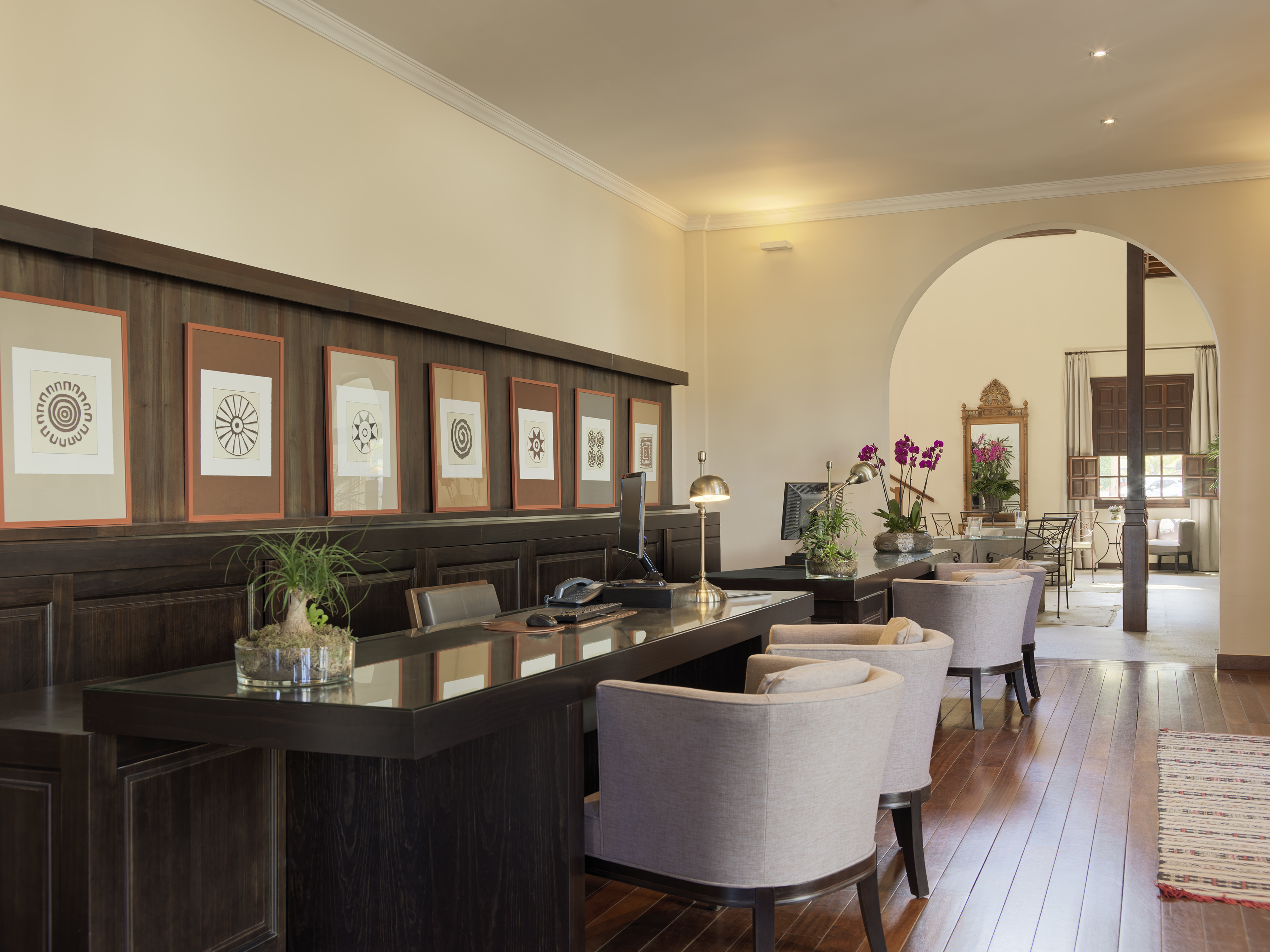 Elegant hotel reception desk with computers, framed art, and warm wood tones.