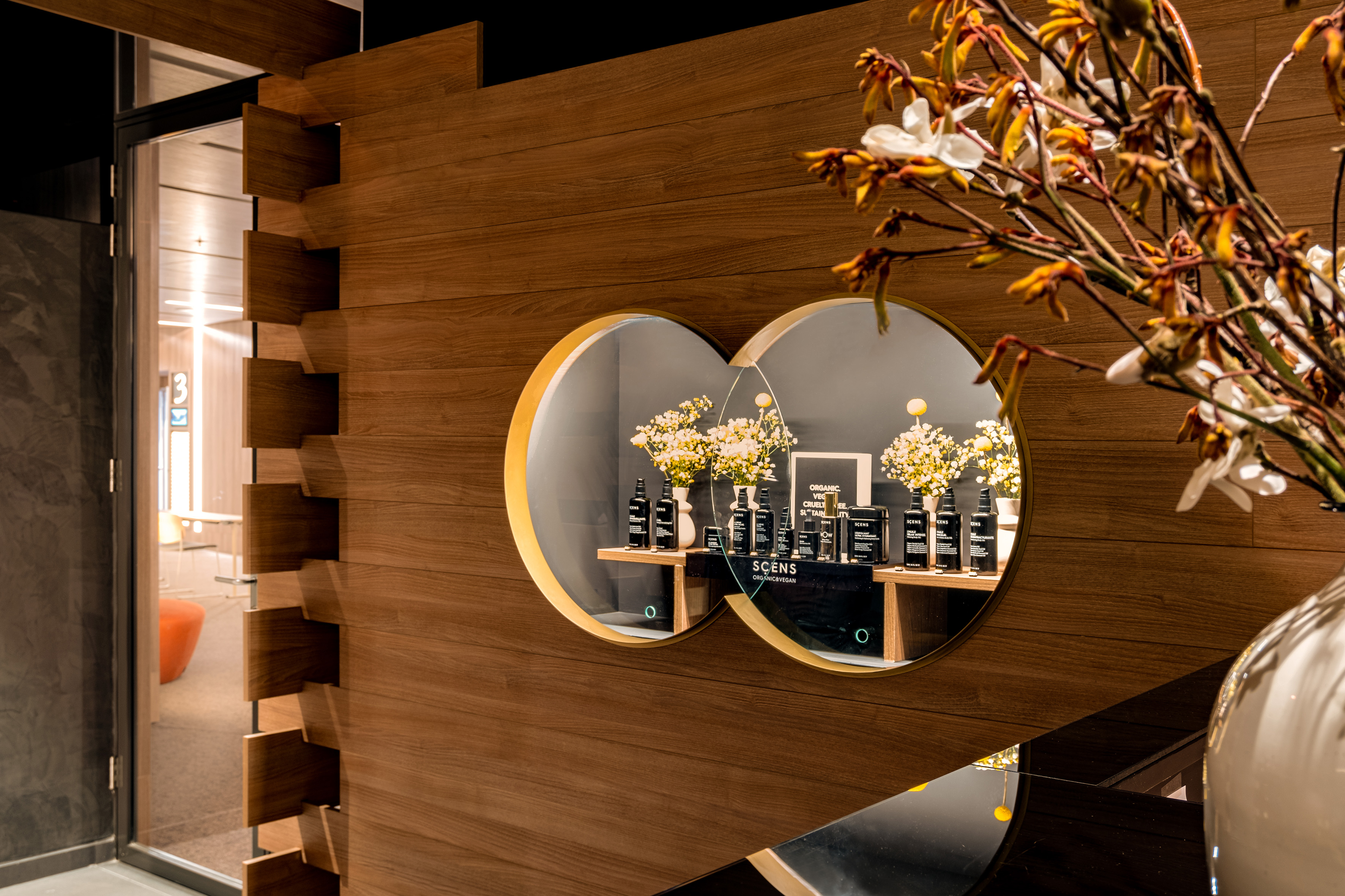 SCENS organic vegan product display in modern wooden interior with circular mirrors.