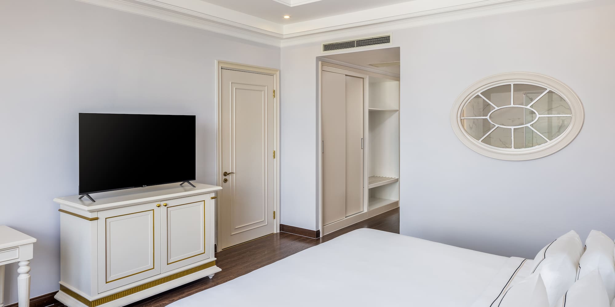 a bedroom with a tv and a white bed