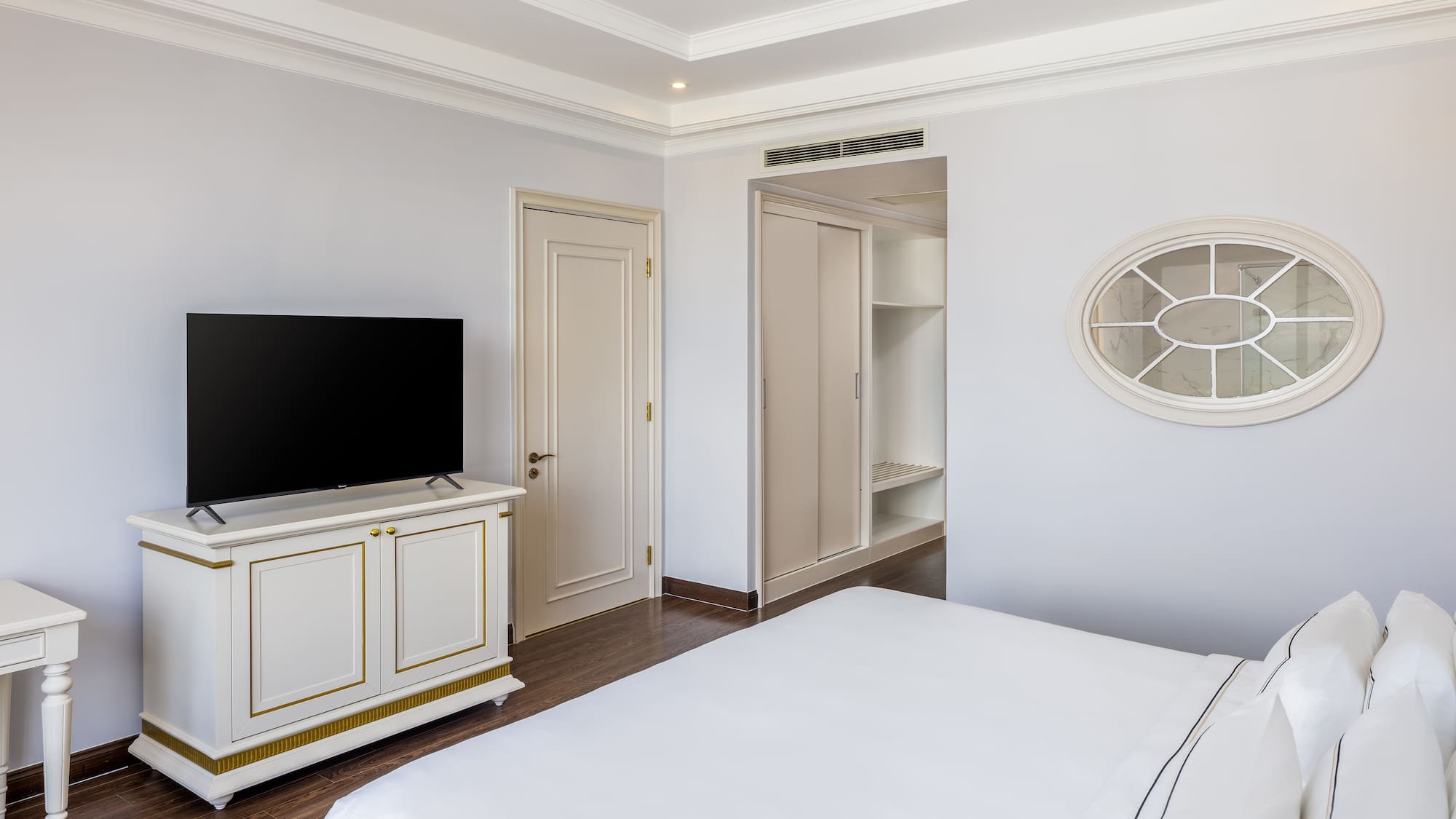 a bedroom with a tv and a white bed