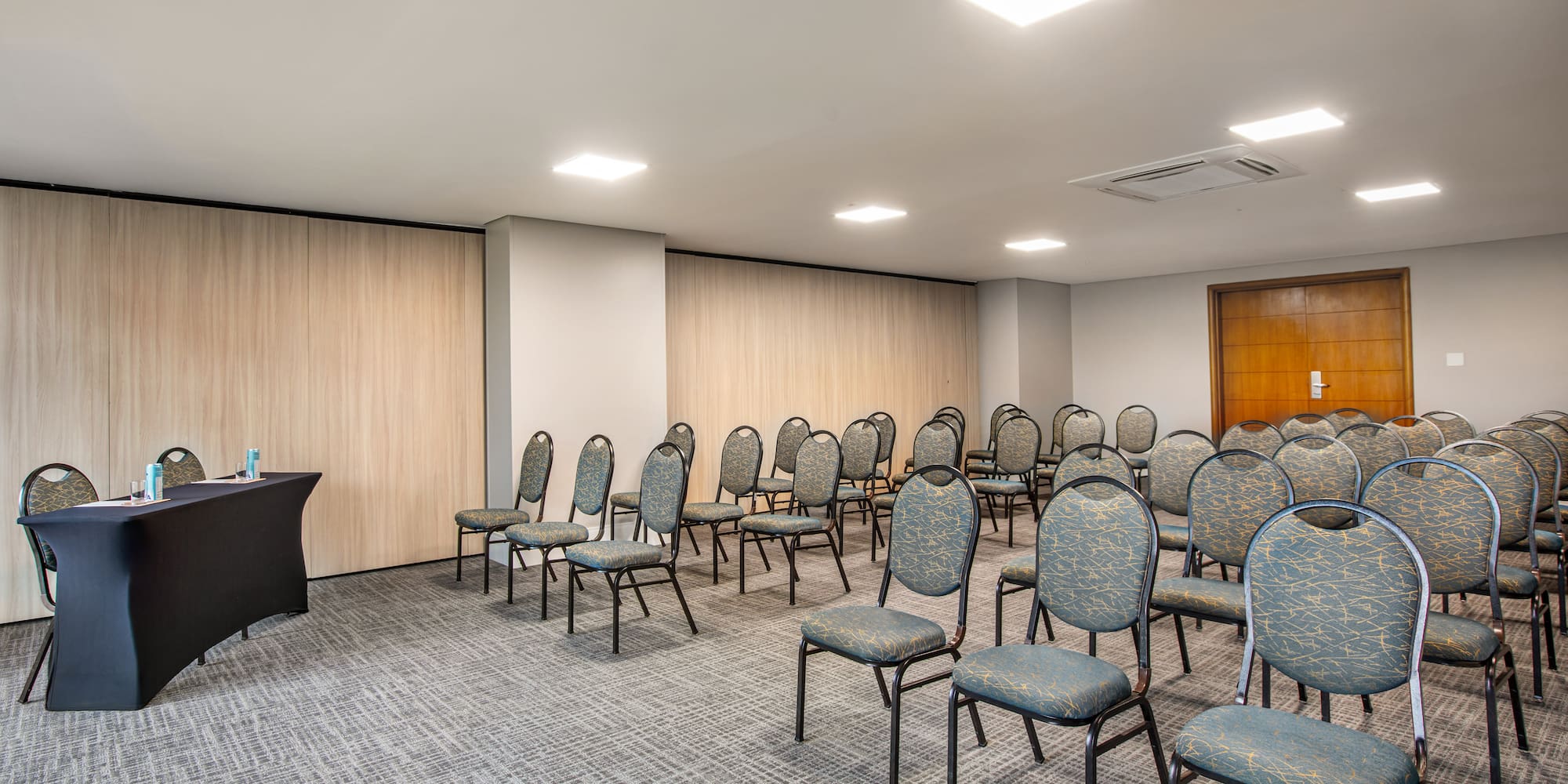 Empty conference room with rows of patterned chairs and black lectern.