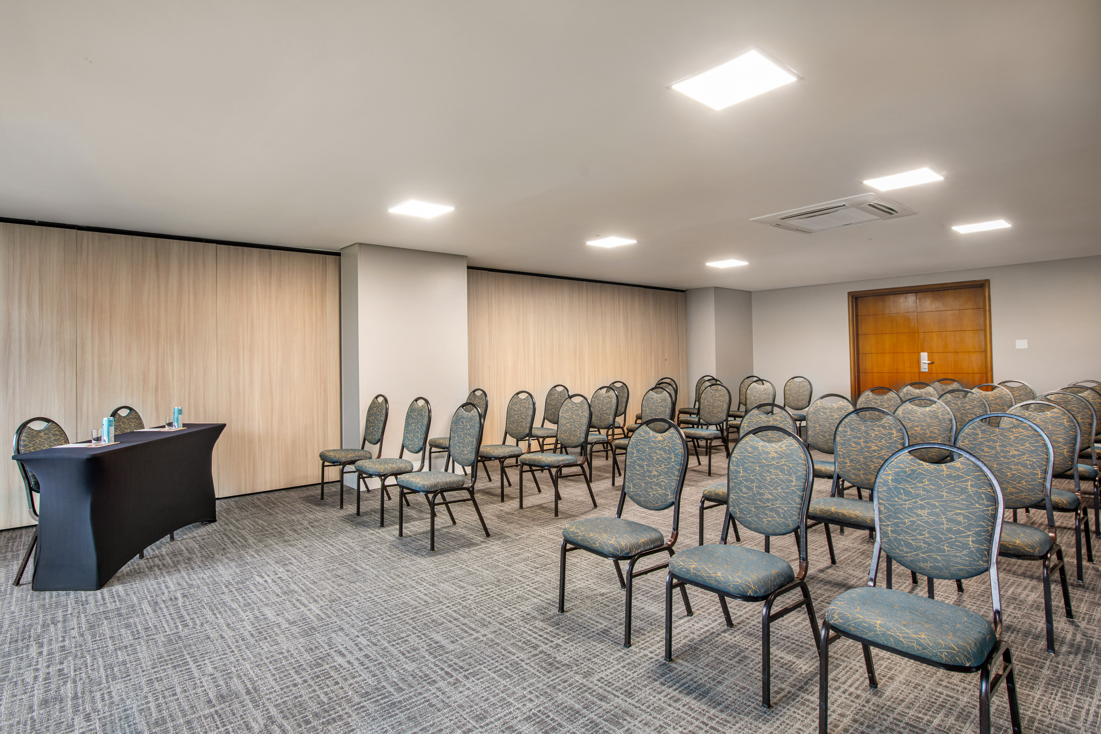 Empty conference room with rows of patterned chairs and black lectern.