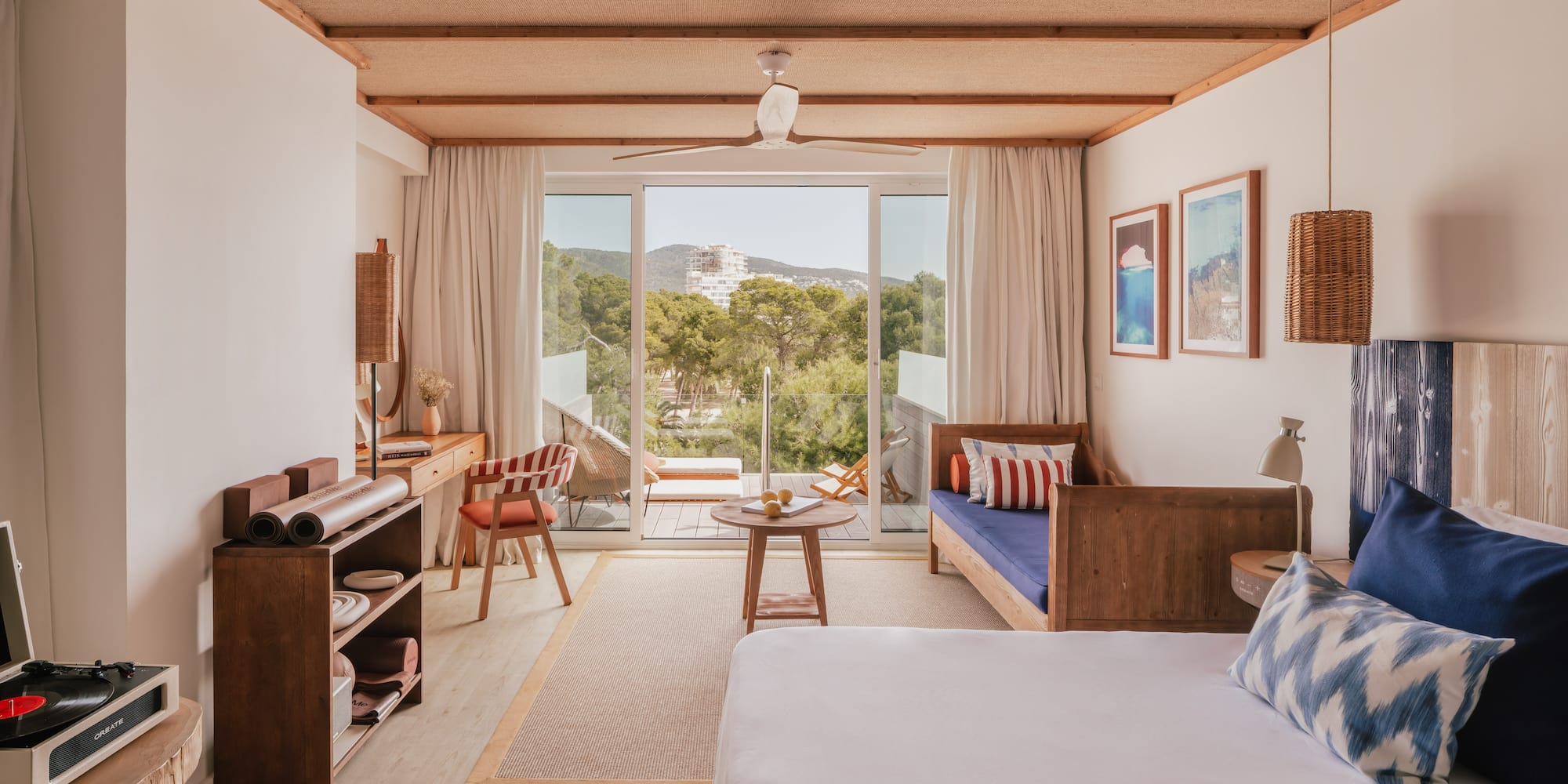 Modern resort room with balcony, nature view, woven ceiling, and wood furniture.