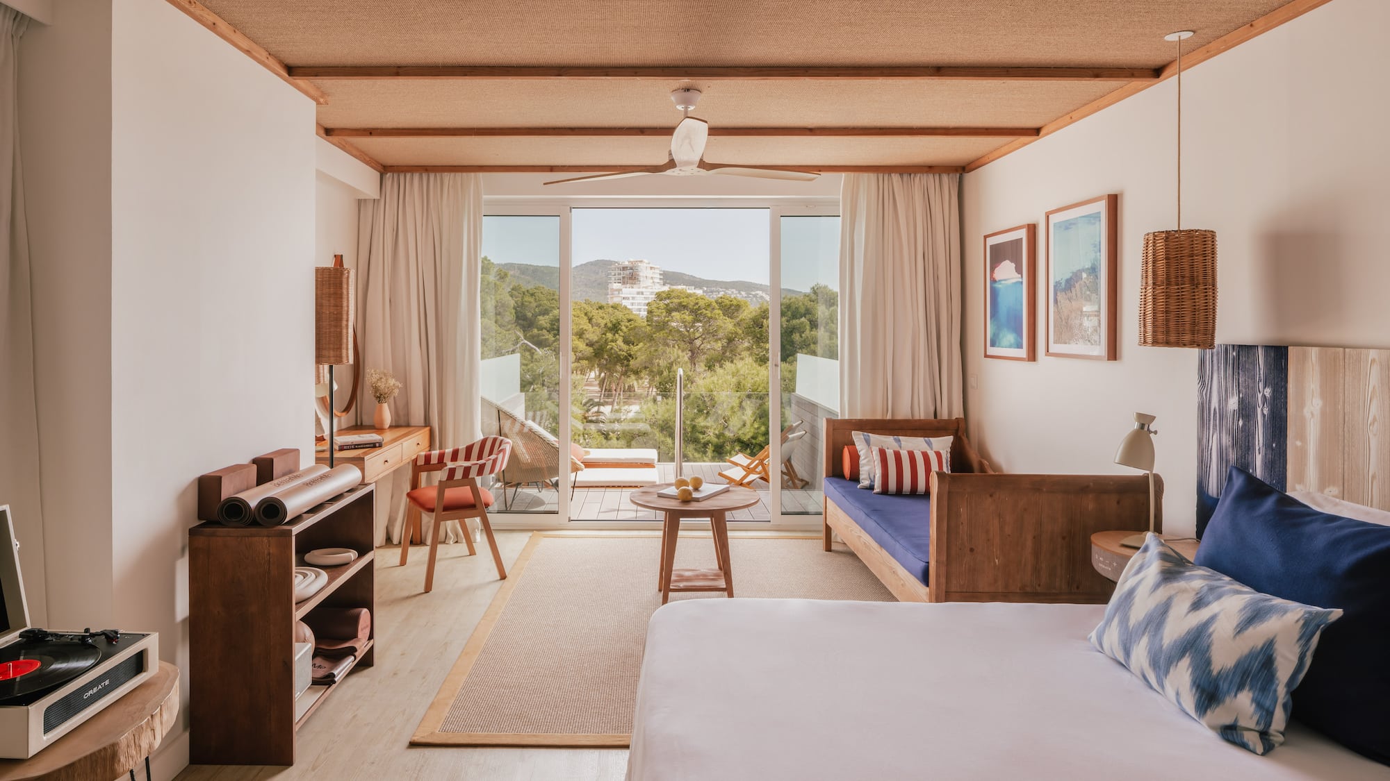 Modern resort room with balcony, nature view, woven ceiling, and wood furniture.