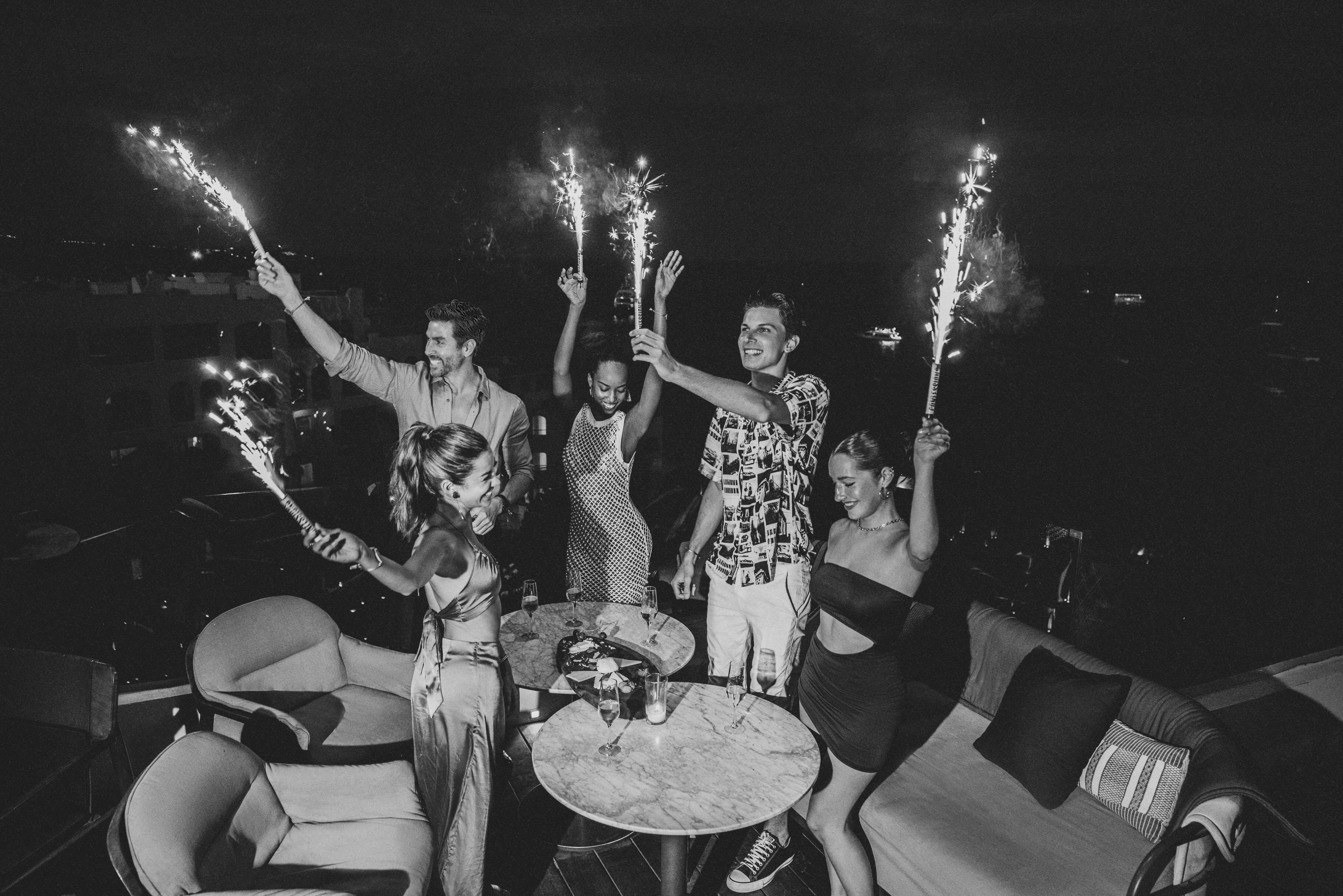 Group of friends celebrating with sparklers at an outdoor night party.