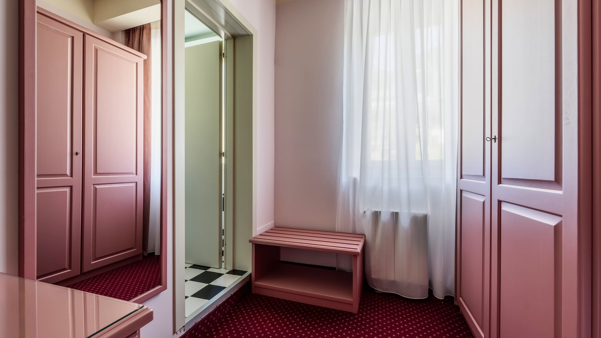 Rose pink bedroom interior with wardrobes, red carpet, and mirror.
