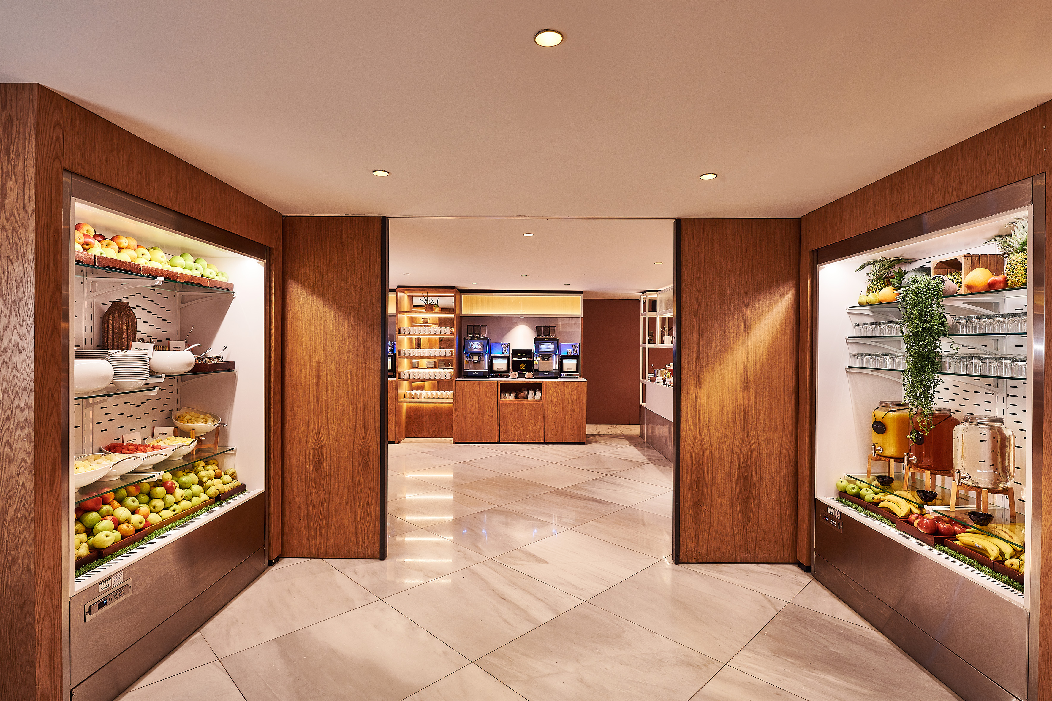 Hotel breakfast buffet with fresh fruit displays, juice, and coffee station.