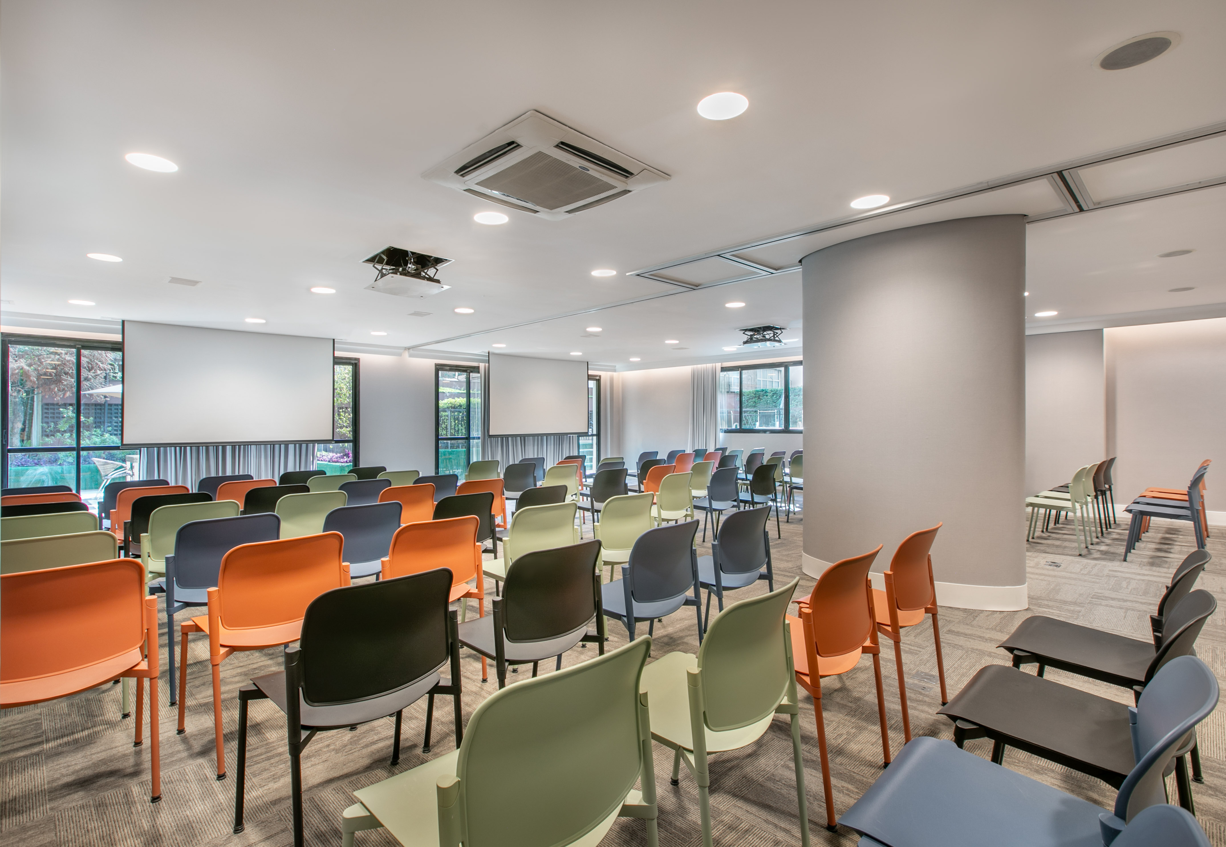 Empty modern conference room with colorful chairs and projector screen.