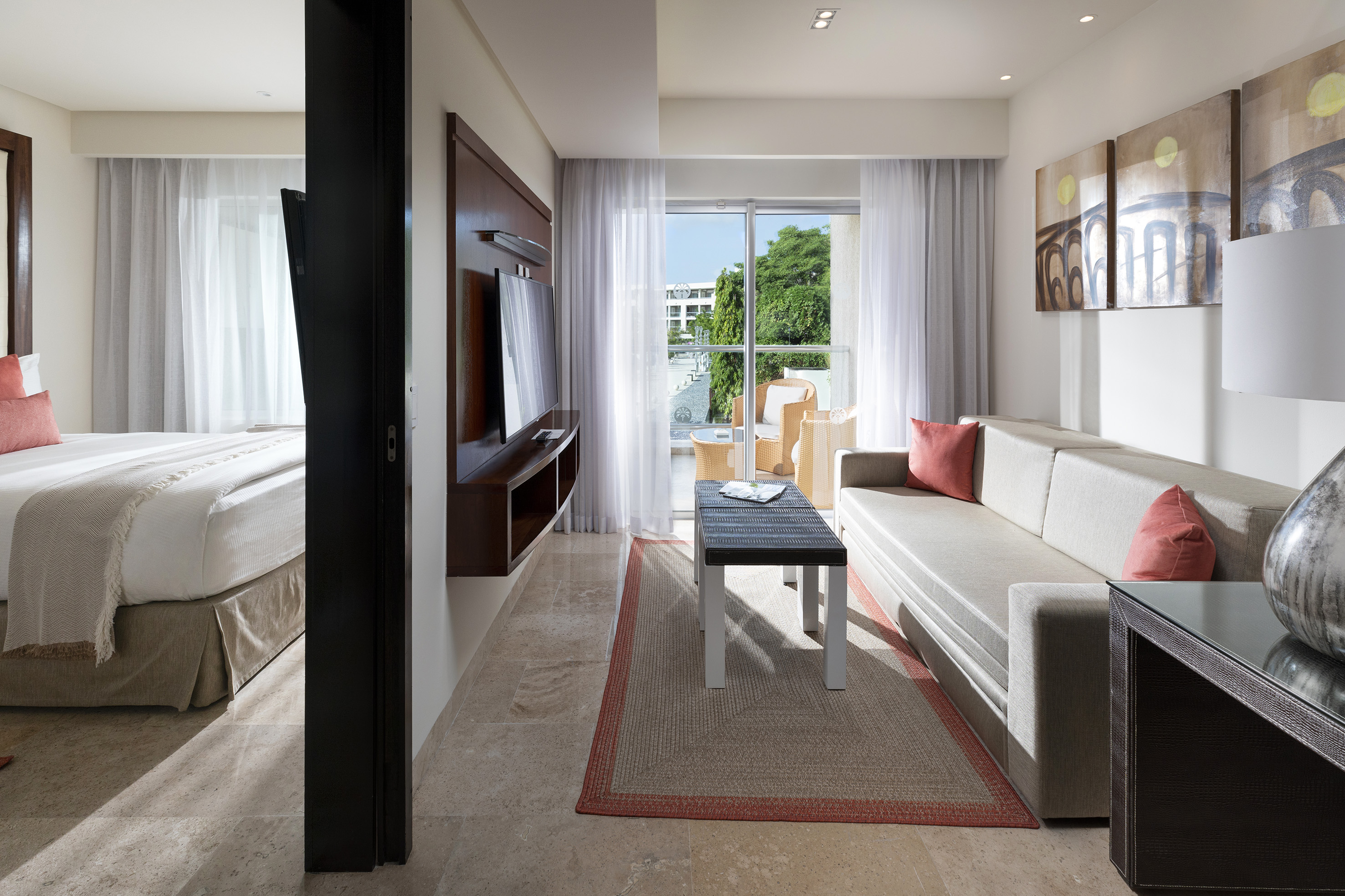 Spacious modern hotel suite with living room, bedroom, and private balcony.