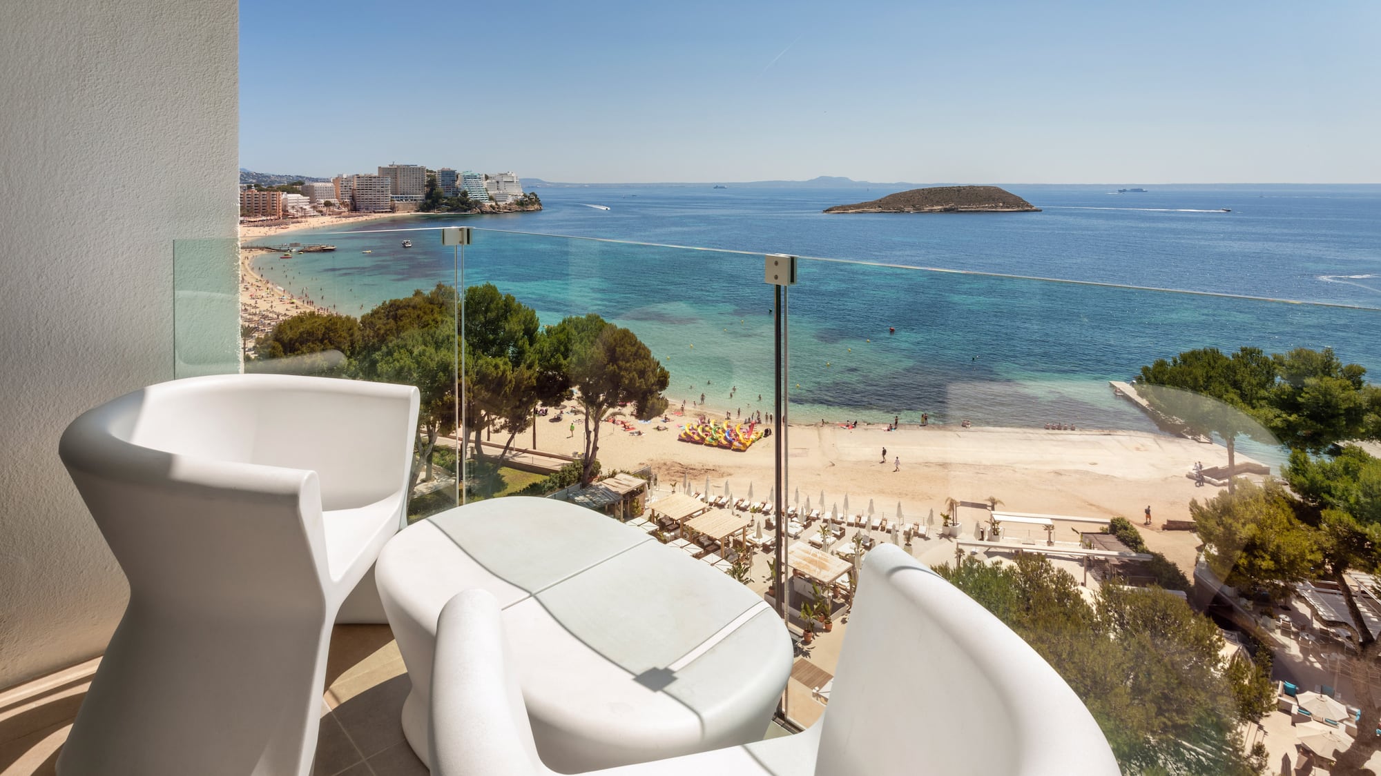 a balcony with chairs and a beach view