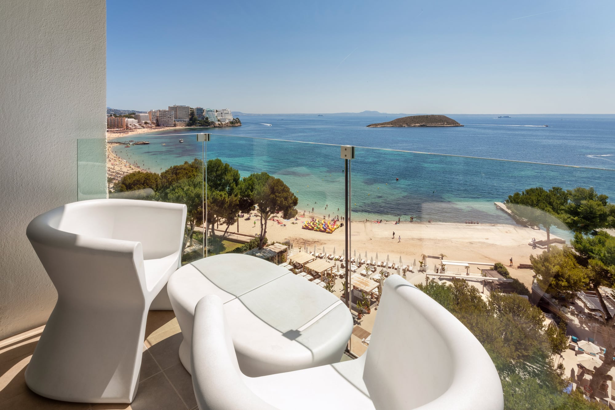 a balcony with chairs and a beach view