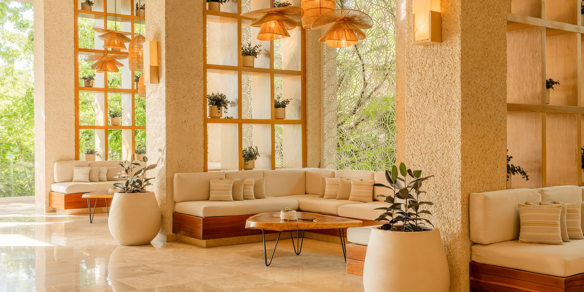 Tropical modern lobby with light sofas, wooden decor, plants, and rattan lamps.