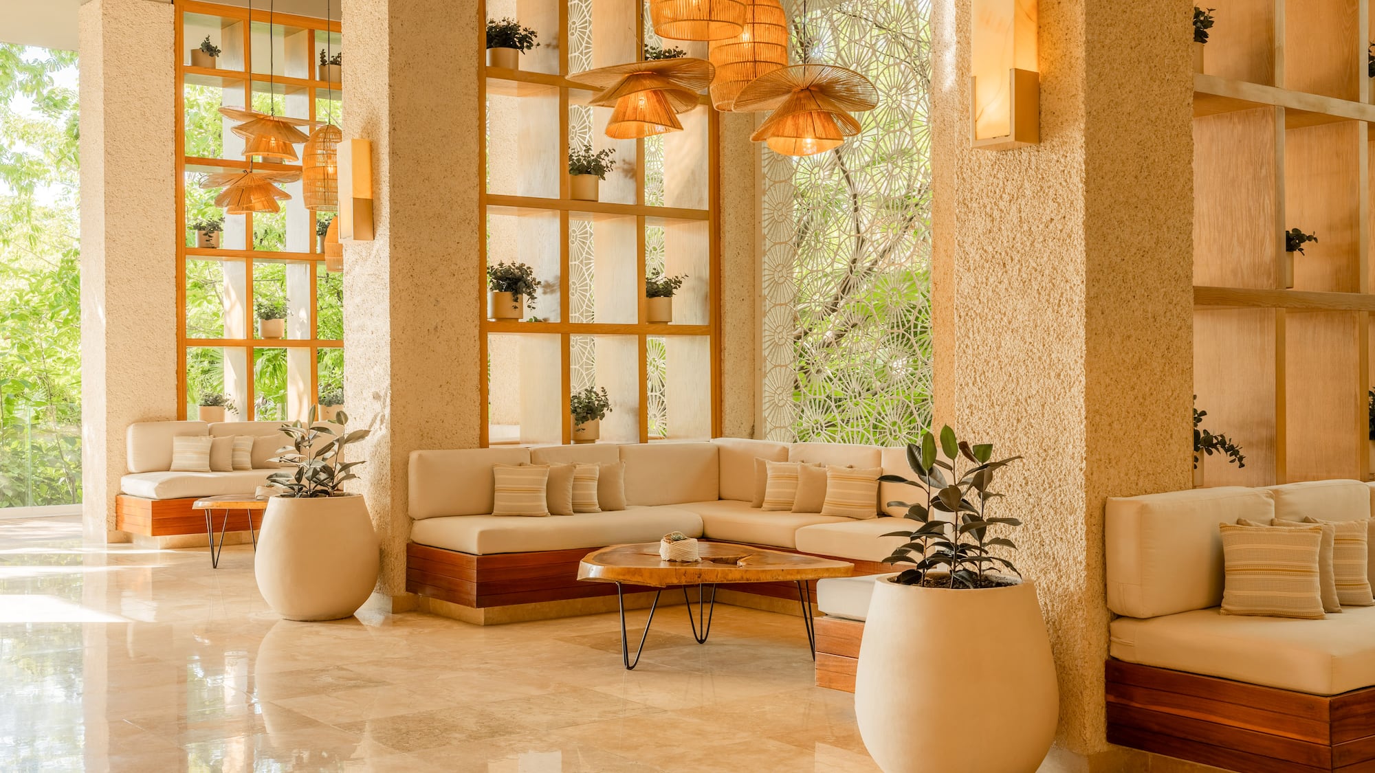 Modern tropical lounge with beige sofas, wood, plants, and natural light.
