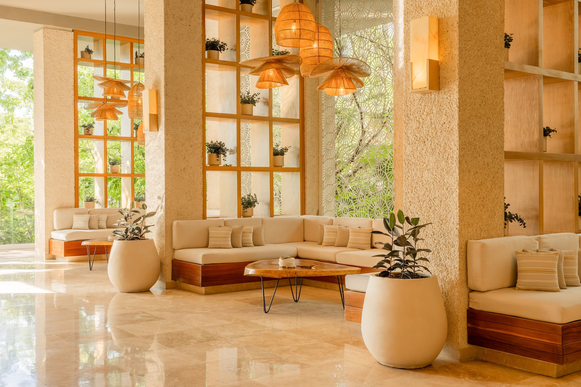 Tropical modern lobby with light sofas, wooden decor, plants, and rattan lamps.
