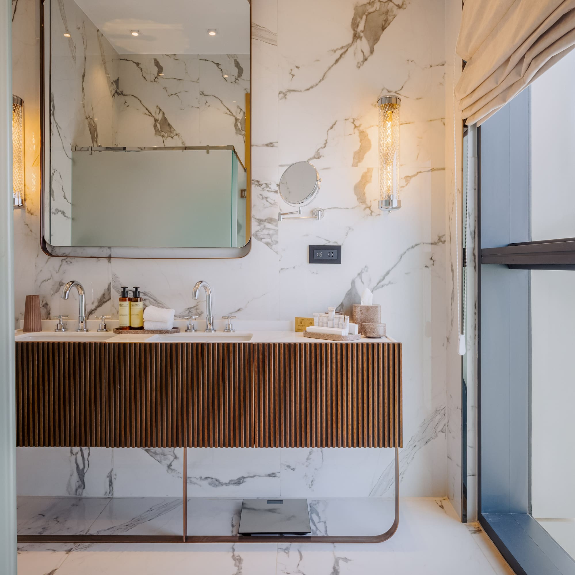 Luxury marble bathroom with double vanity, modern design, and city view from window.