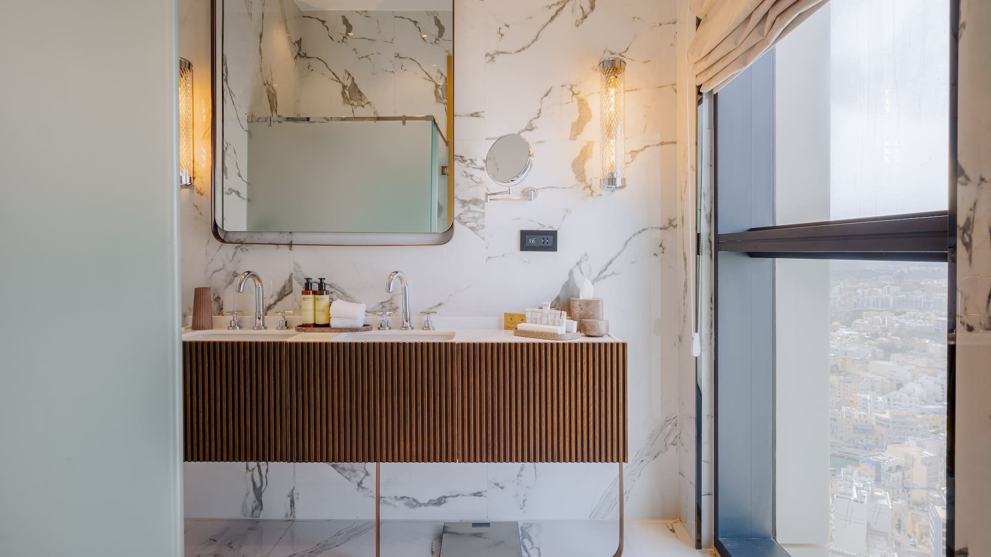 Luxury marble bathroom with double vanity, modern design, and city view from window.