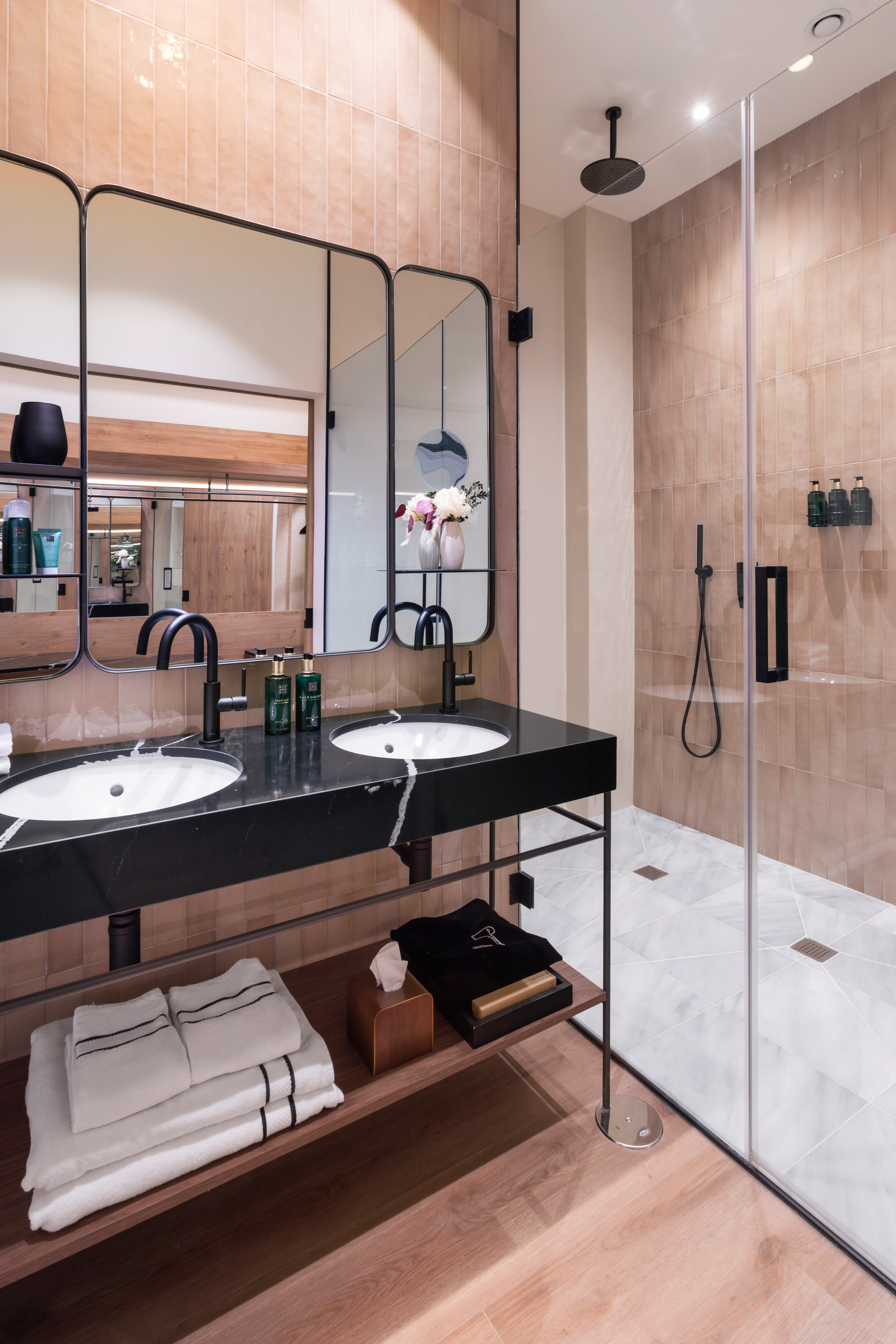 Modern bathroom: double black marble vanity, terracotta tiles, glass shower.