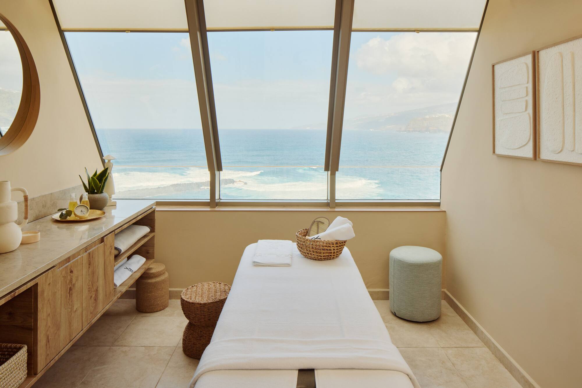Coastal spa massage room with ocean view, treatment table, and natural decor.