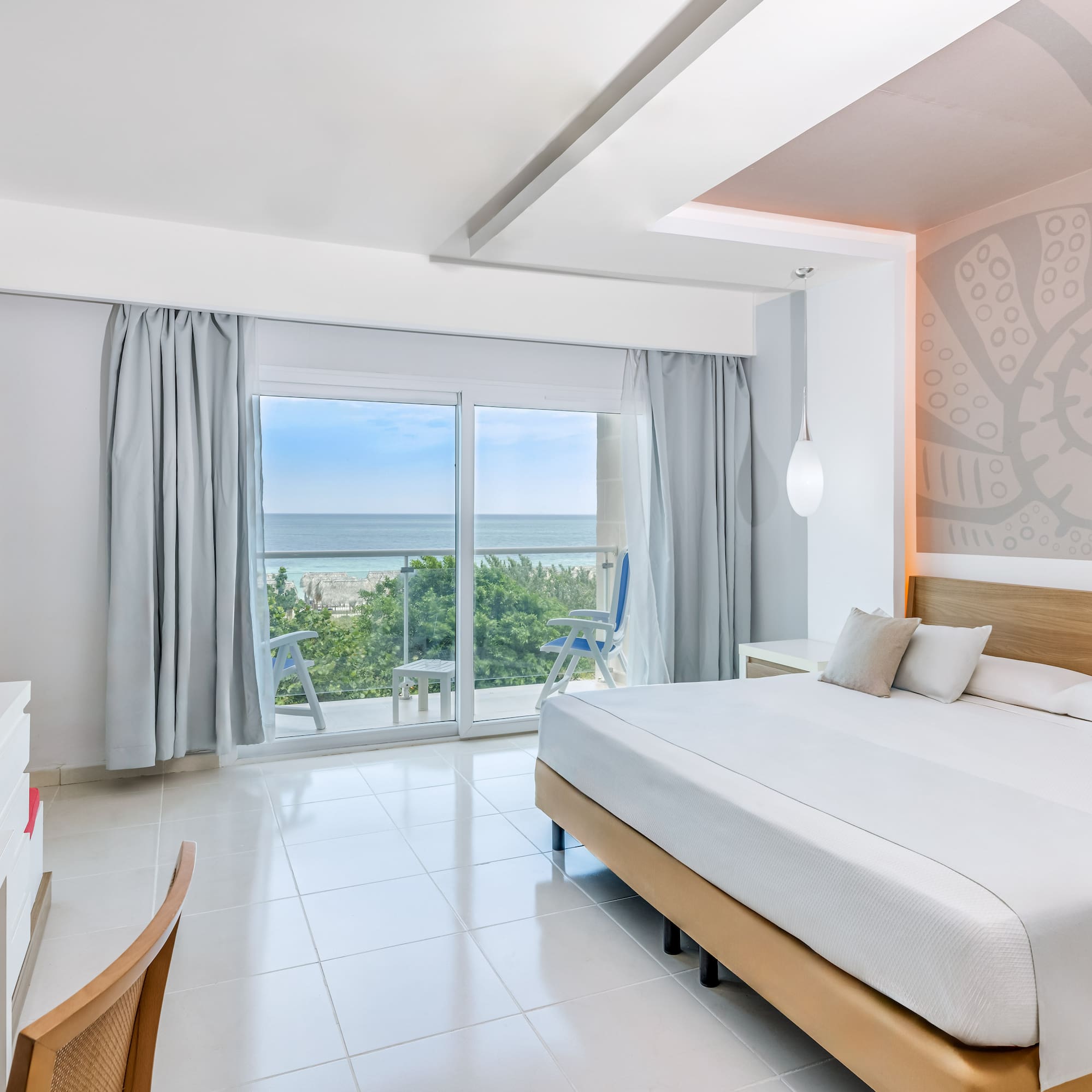 a bedroom with a large window and a view of the ocean