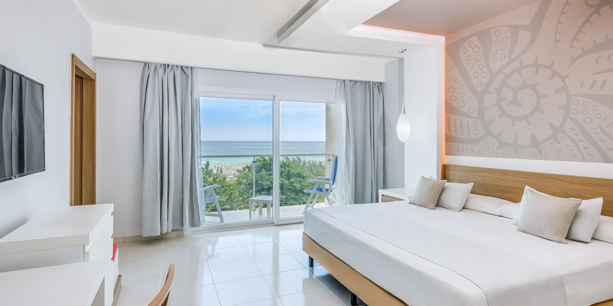a bedroom with a large window and a view of the ocean